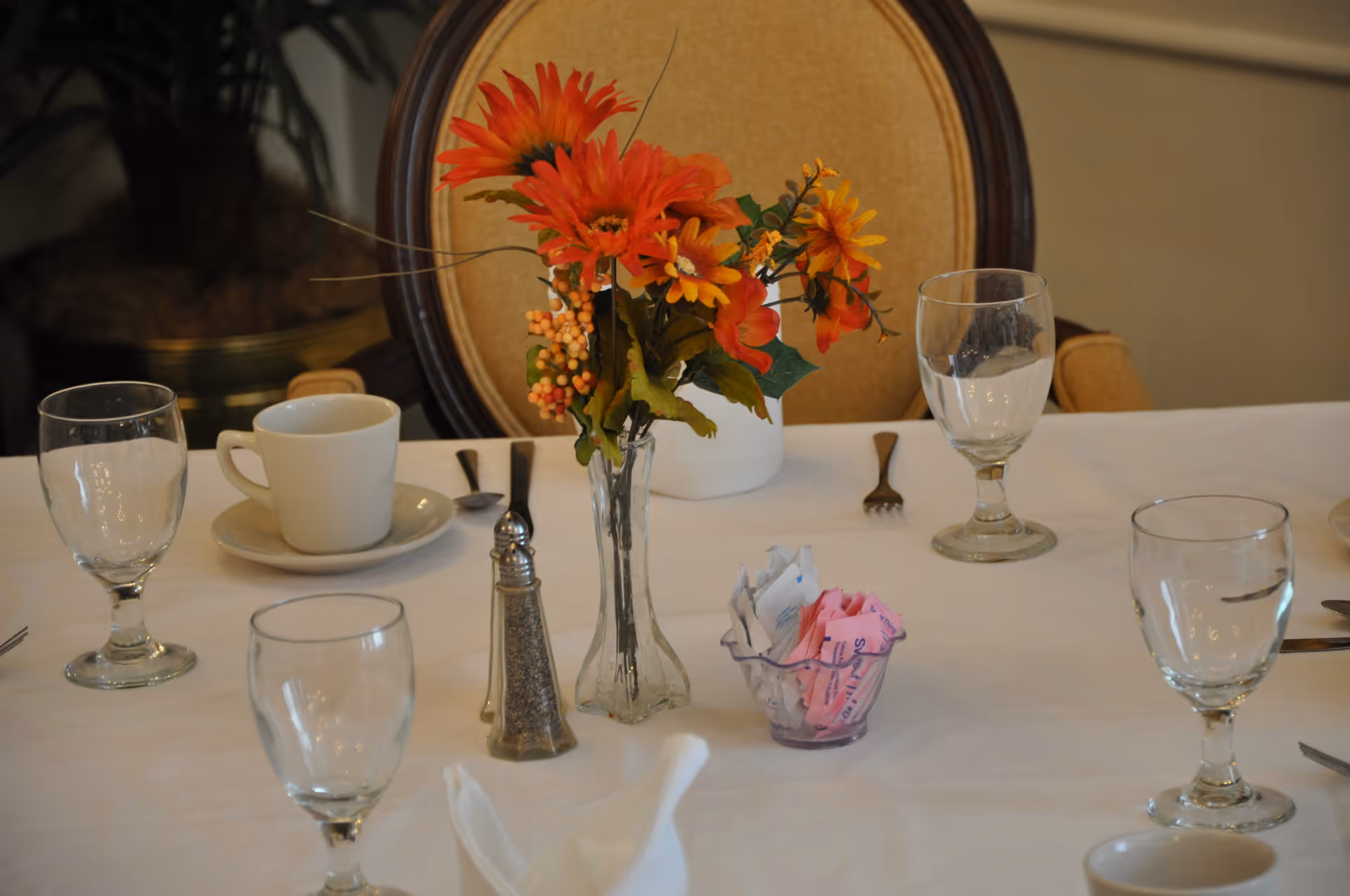 Dining table setting with floral centerpiece, glassware, cups, and napkins.