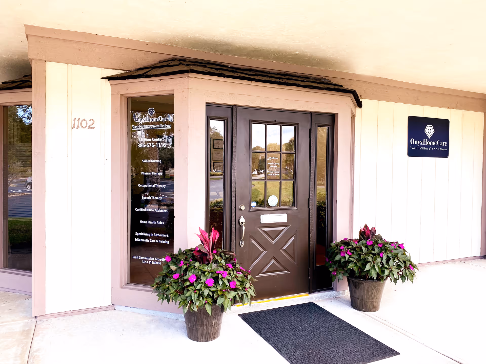 Front entrance of Onyx Home Care building with brown door and potted plants