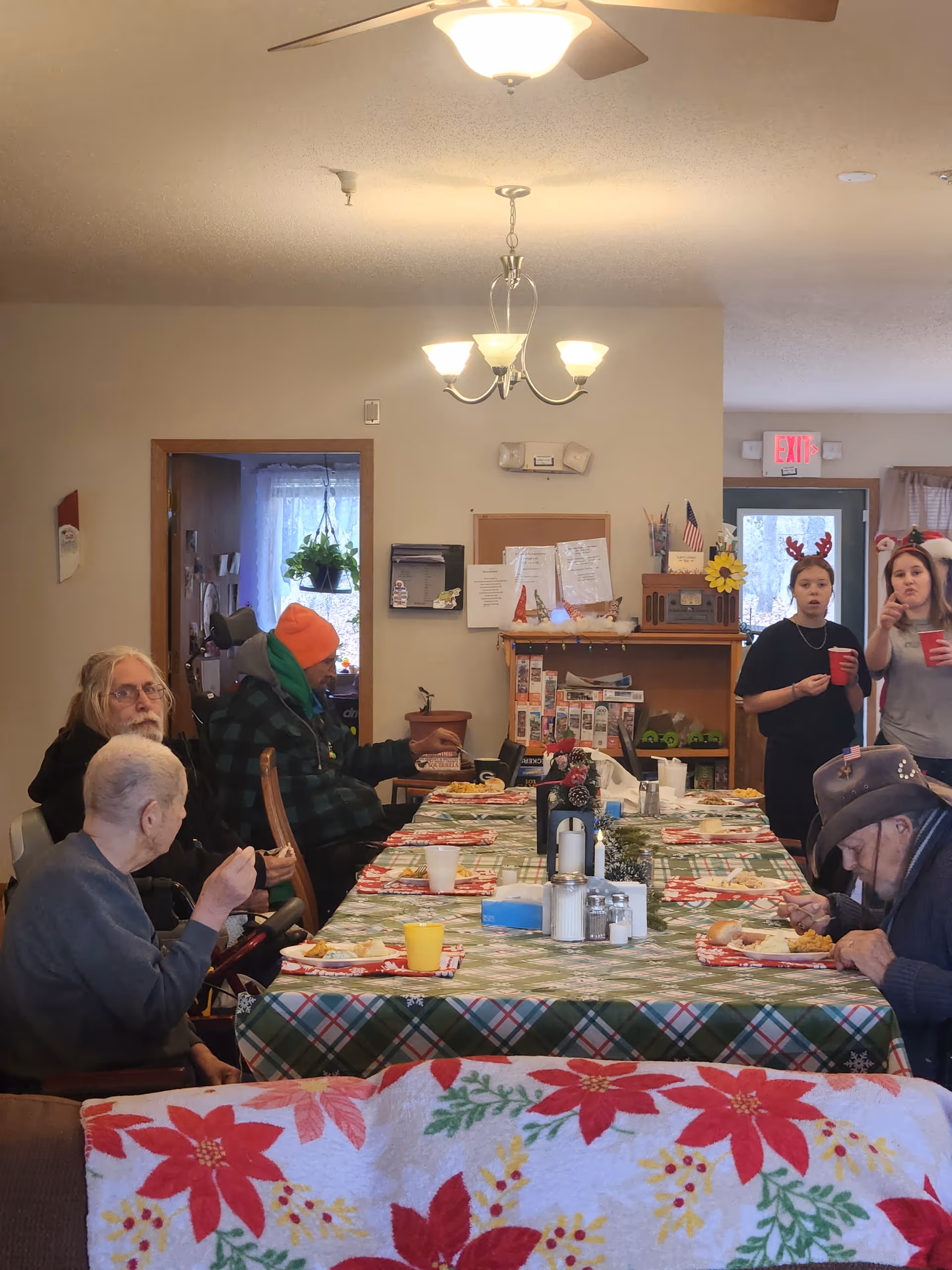 Residents dine at a table with a plaid tablecloth in a cozy senior living dining room.