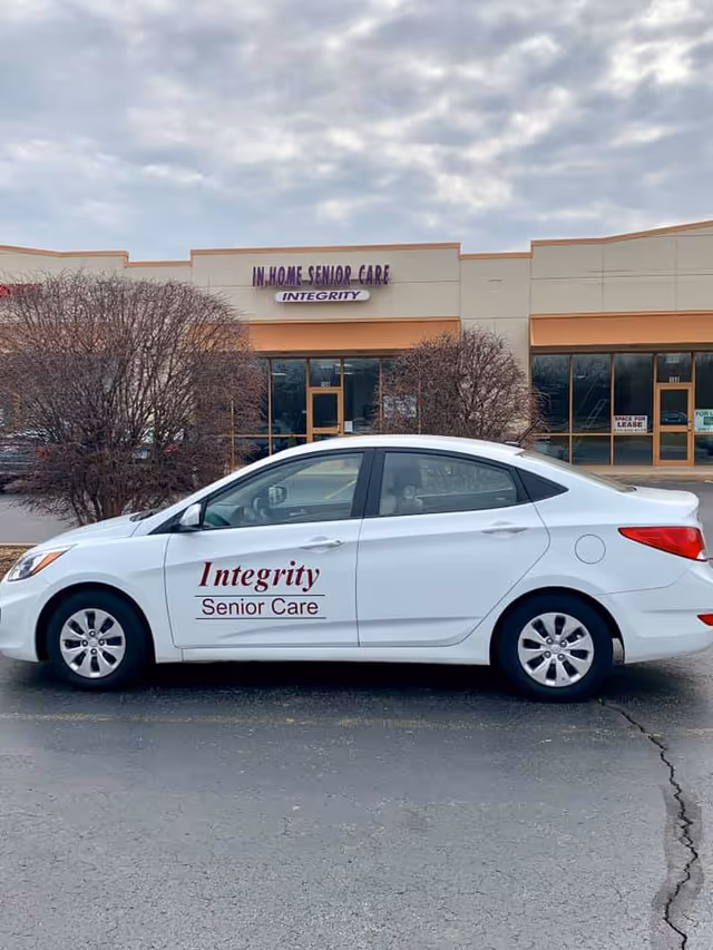 White Integrity Senior Care car parked in front of a storefront building with signage.