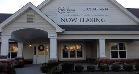 Exterior view of Heartsong Memory Care facility with a Now Leasing sign and entrance.