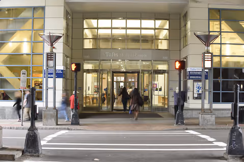 Exterior of Tufts Medicine Home Infusion Services entrance with glass doors and pedestrians