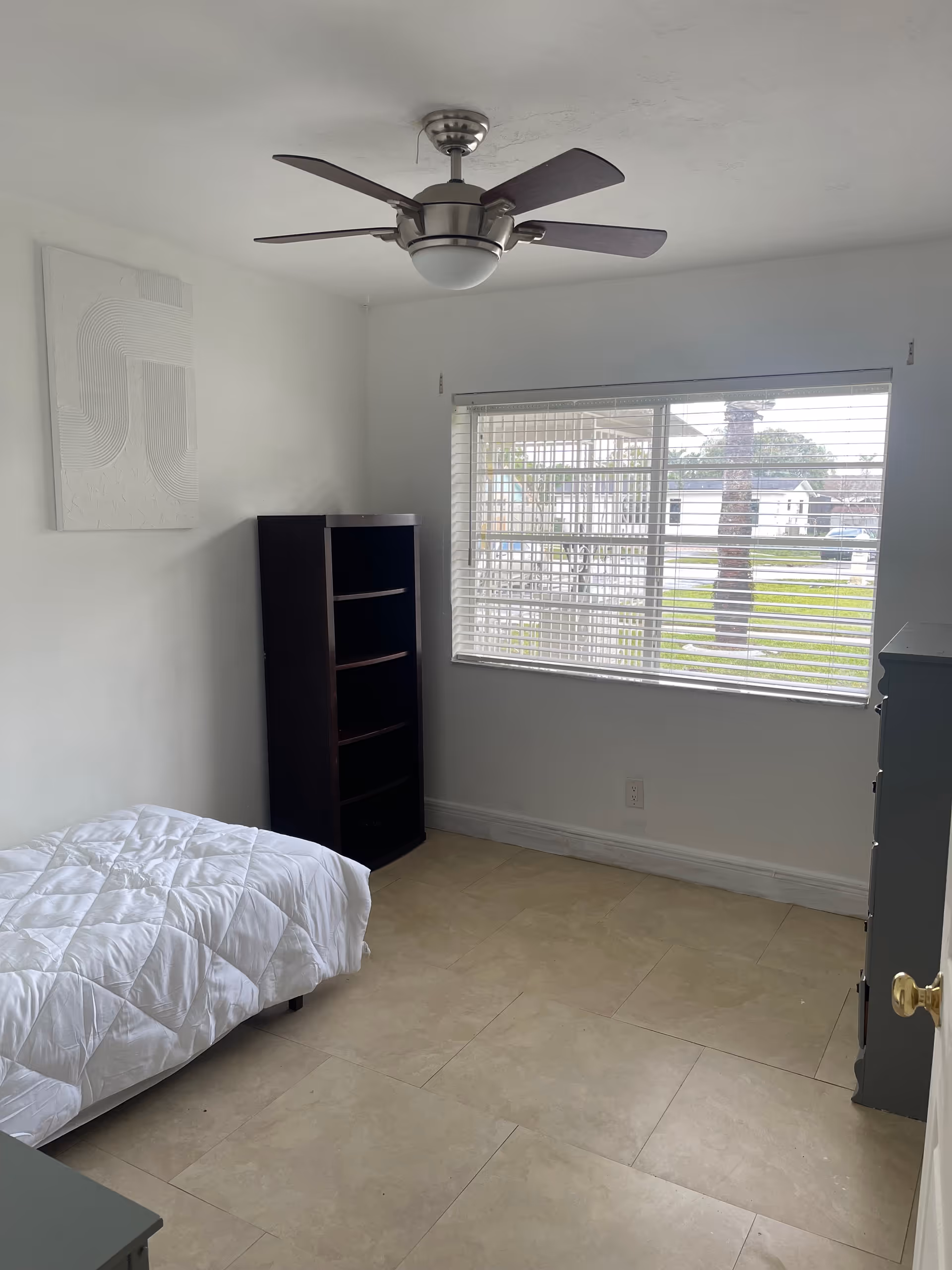 Small bedroom with a bed, dresser, bookshelf, window blinds, and a ceiling fan.