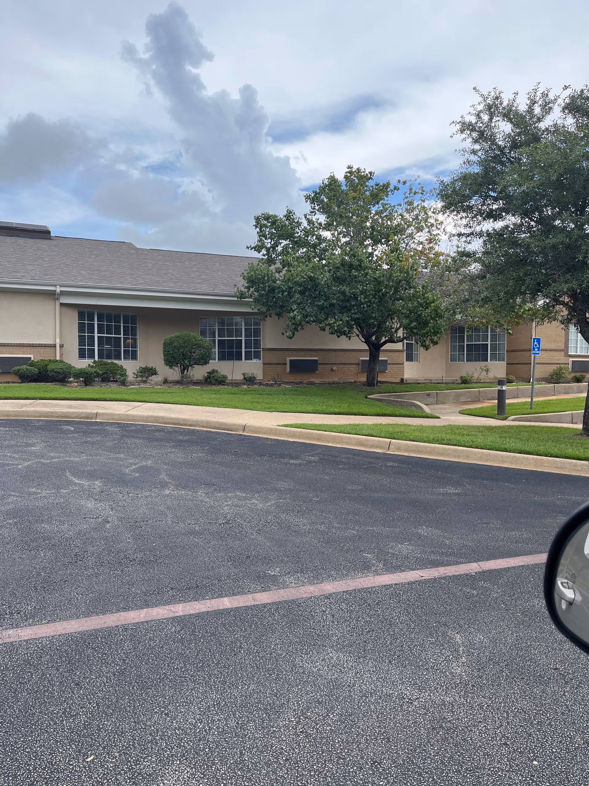 Brookdale Henderson exterior with a parking lot, trees, and a front lawn.