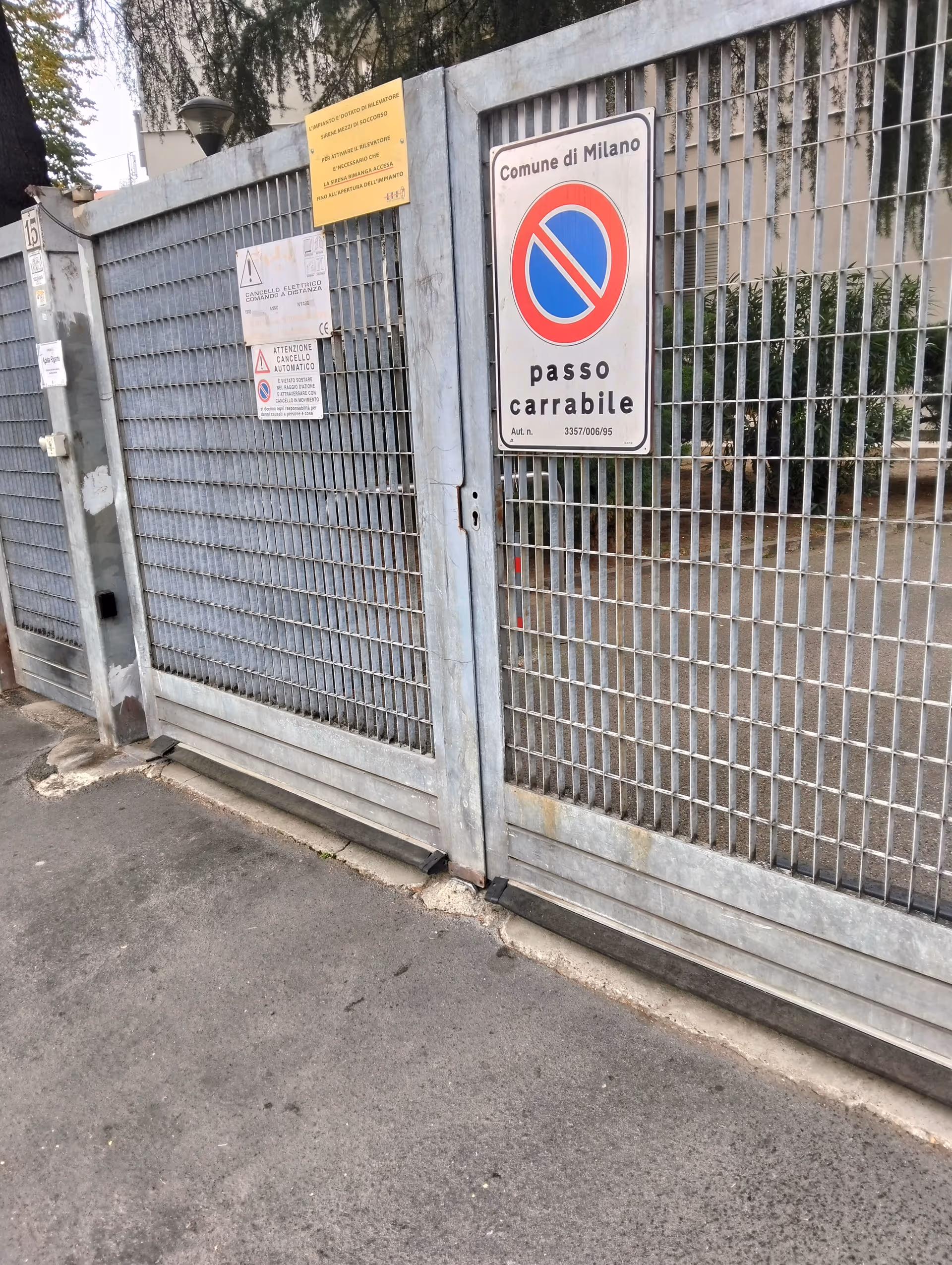 A metal gate with multiple warning signs at a facility entrance.