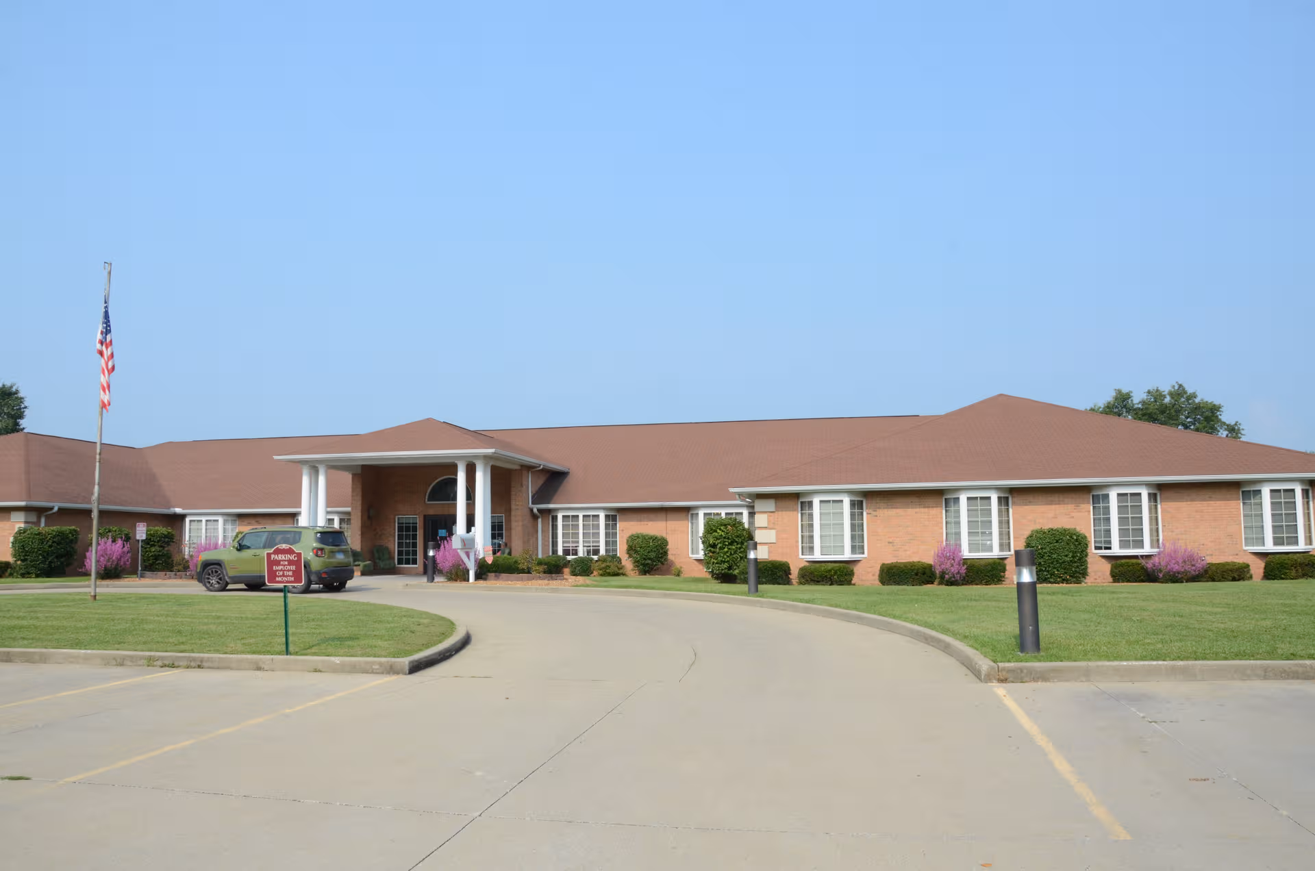 Single-story brick senior living facility with a curved driveway and manicured lawn.