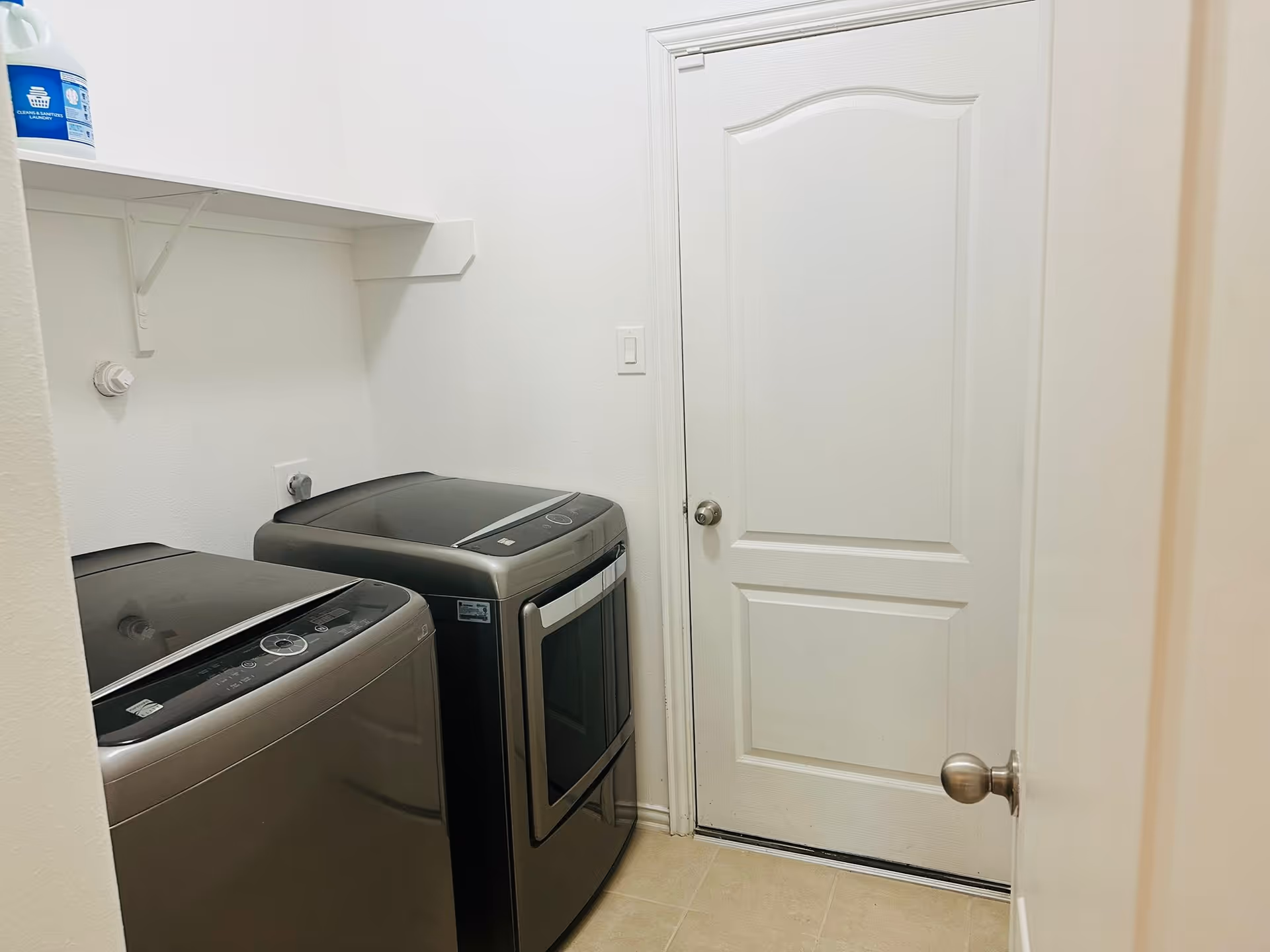 Laundry room with washing machine and dryer beside a white door