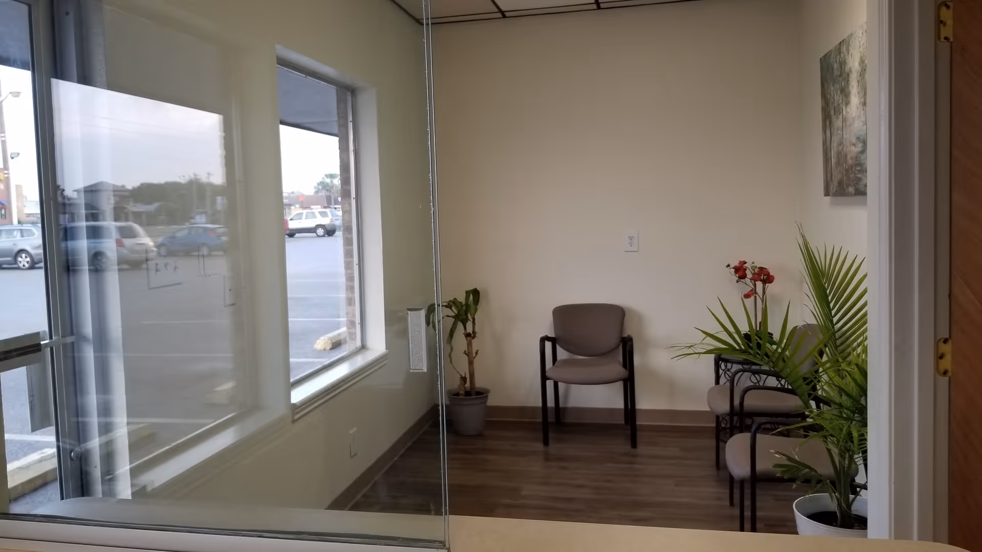 Interior waiting area with glass walls, chairs, and potted plants.
