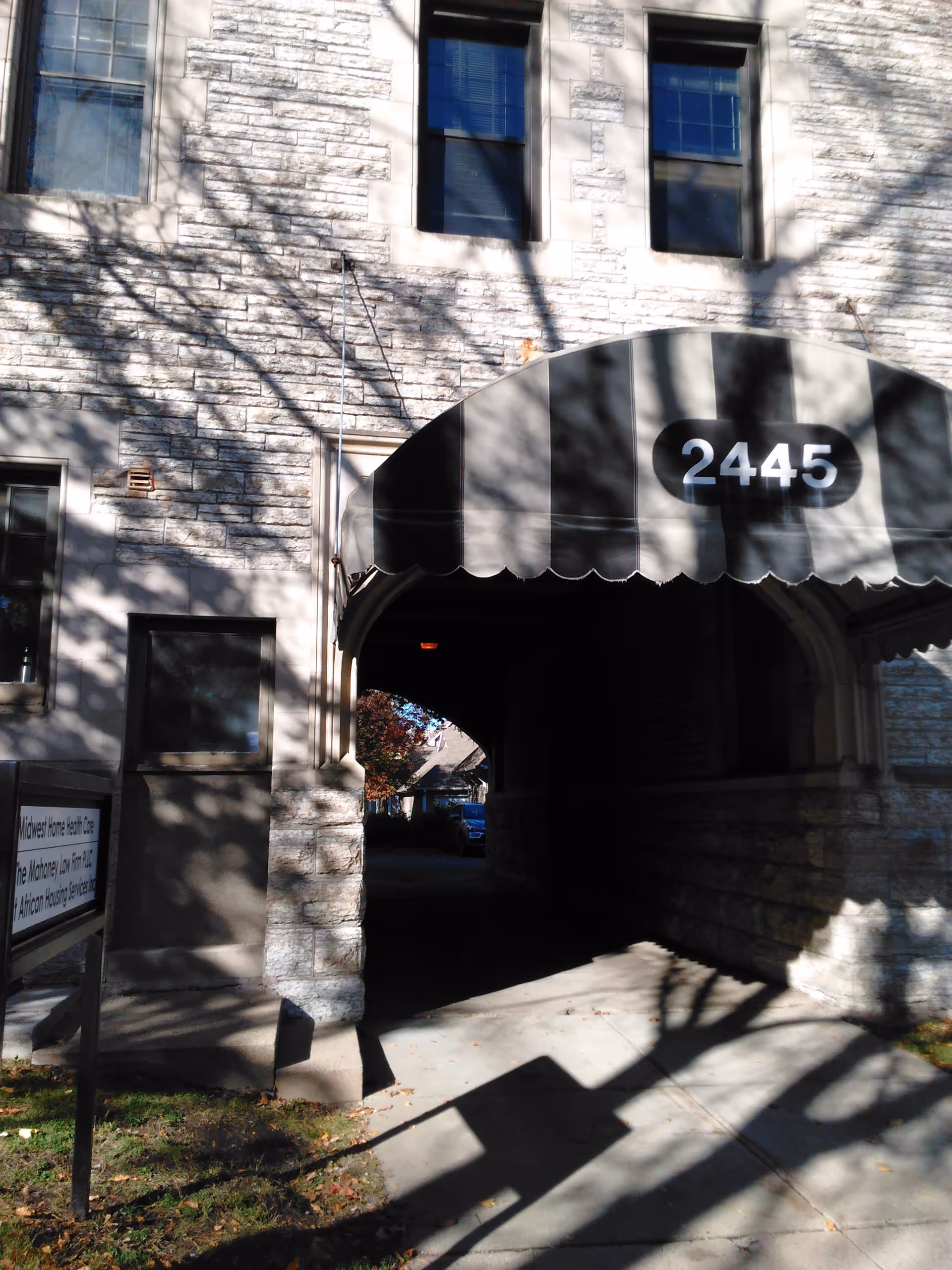 Stone building exterior with an arched doorway canopy and the address 2445.