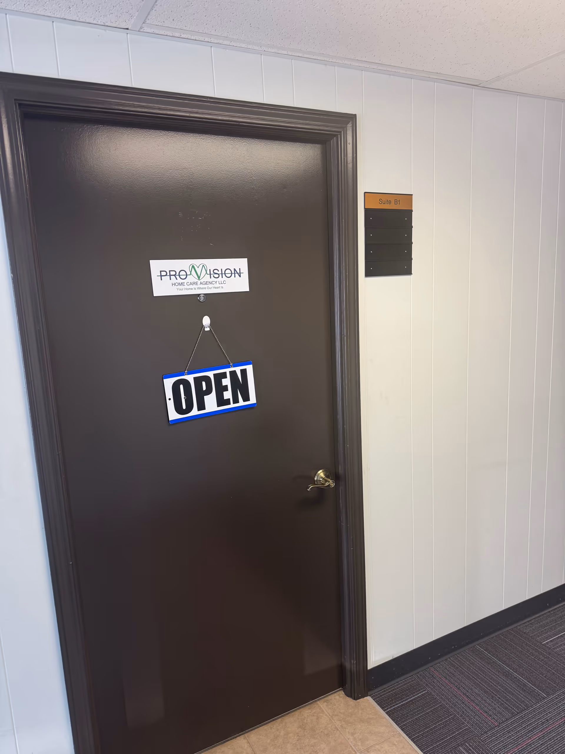Brown door in a hallway with an OPEN sign and ProVision logo.