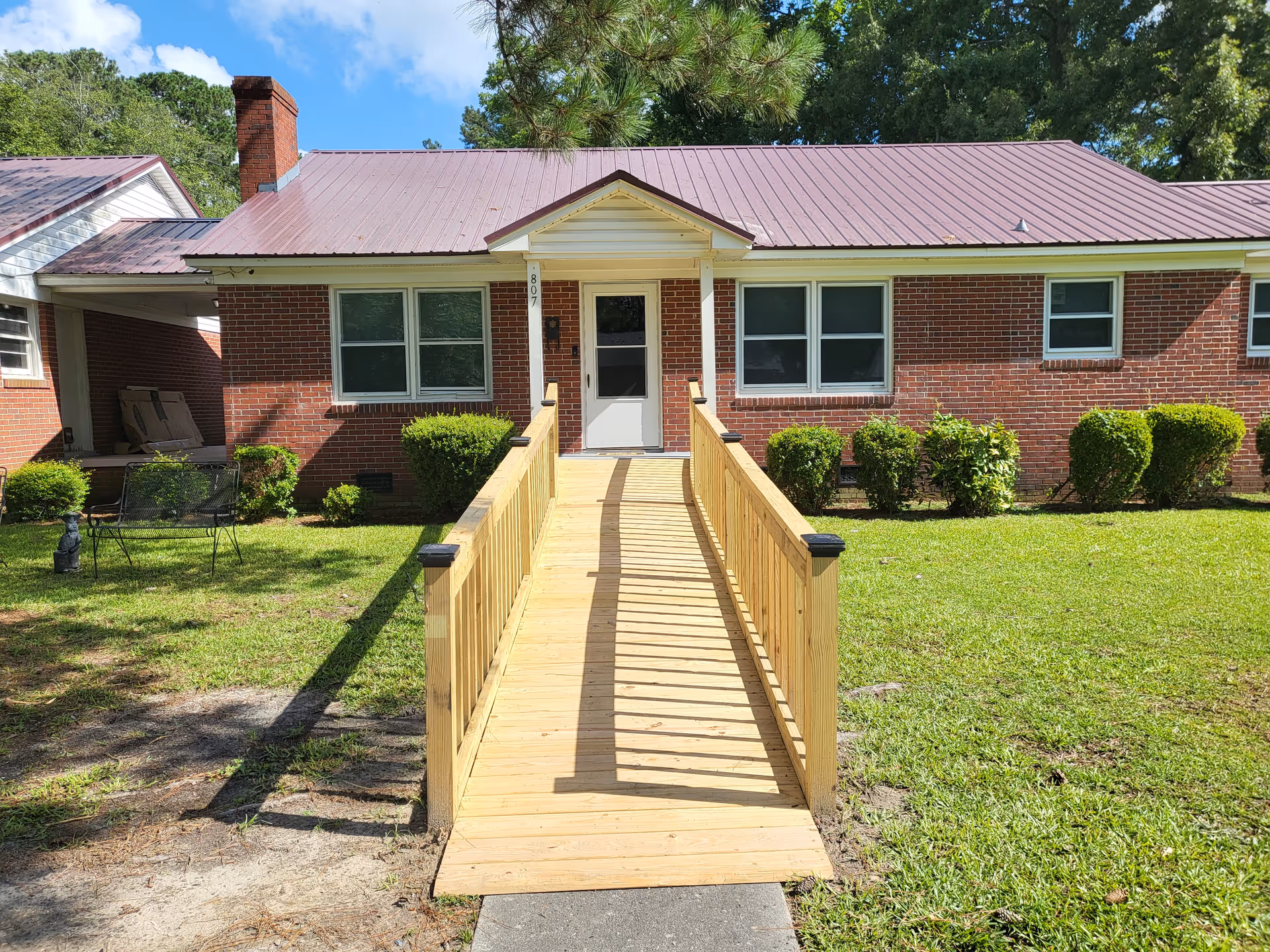Front view of a brick senior living facility with a wooden ramp to the entrance.
