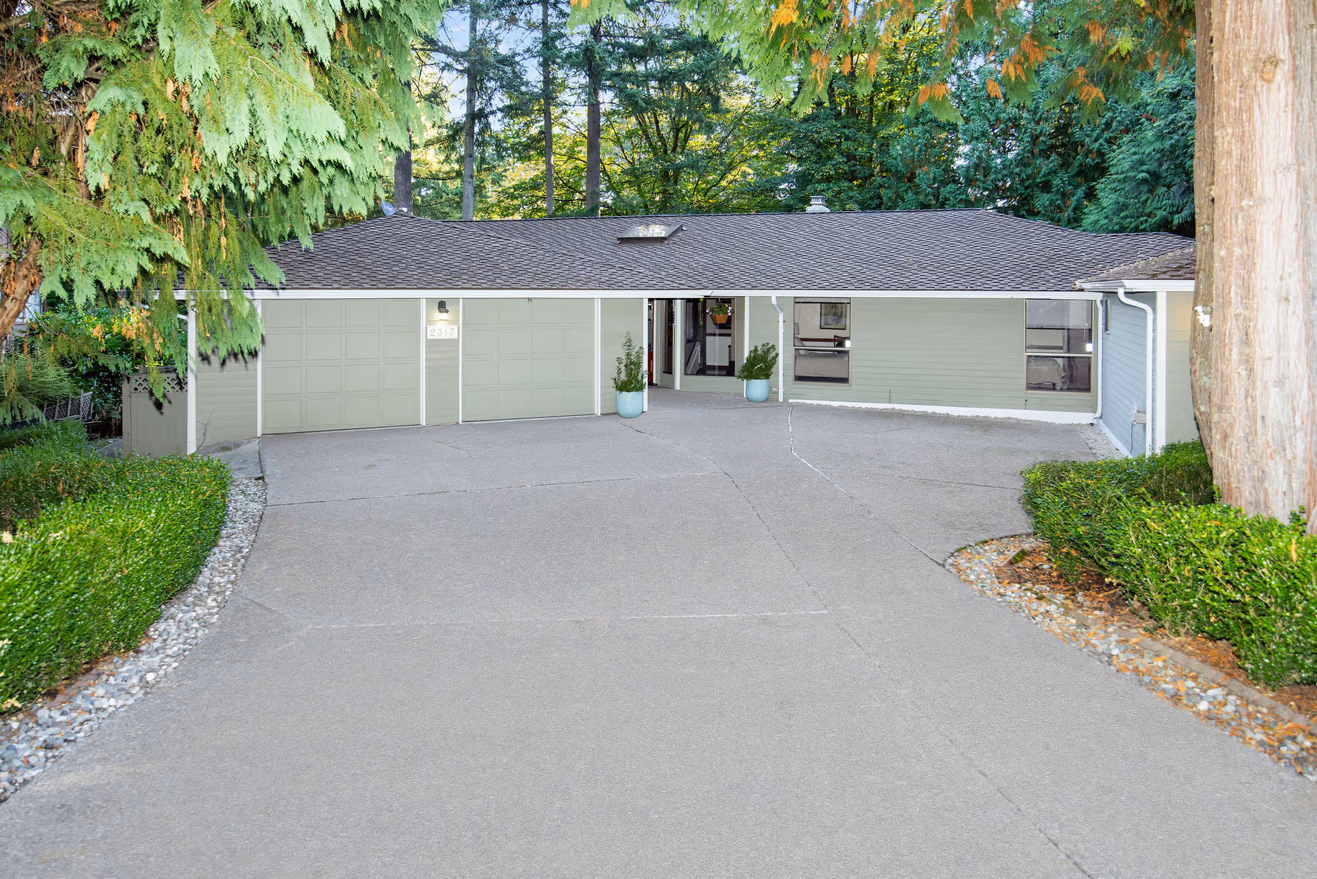 Single-story senior care facility exterior with a wide driveway, garages, and surrounding greenery.