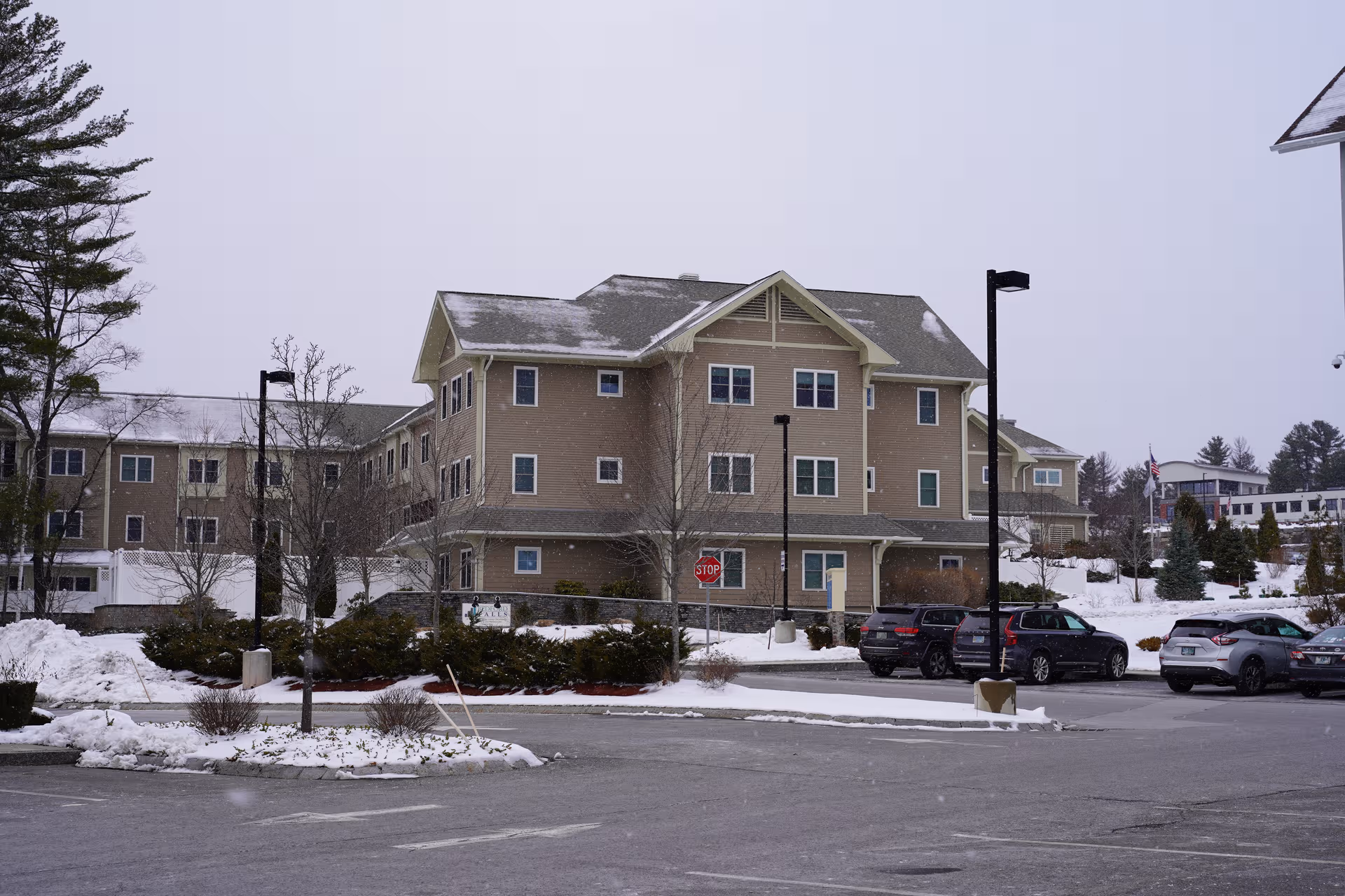 Outside view of Benchmark at Bedford Falls building with parked cars and snow-covered landscaping.