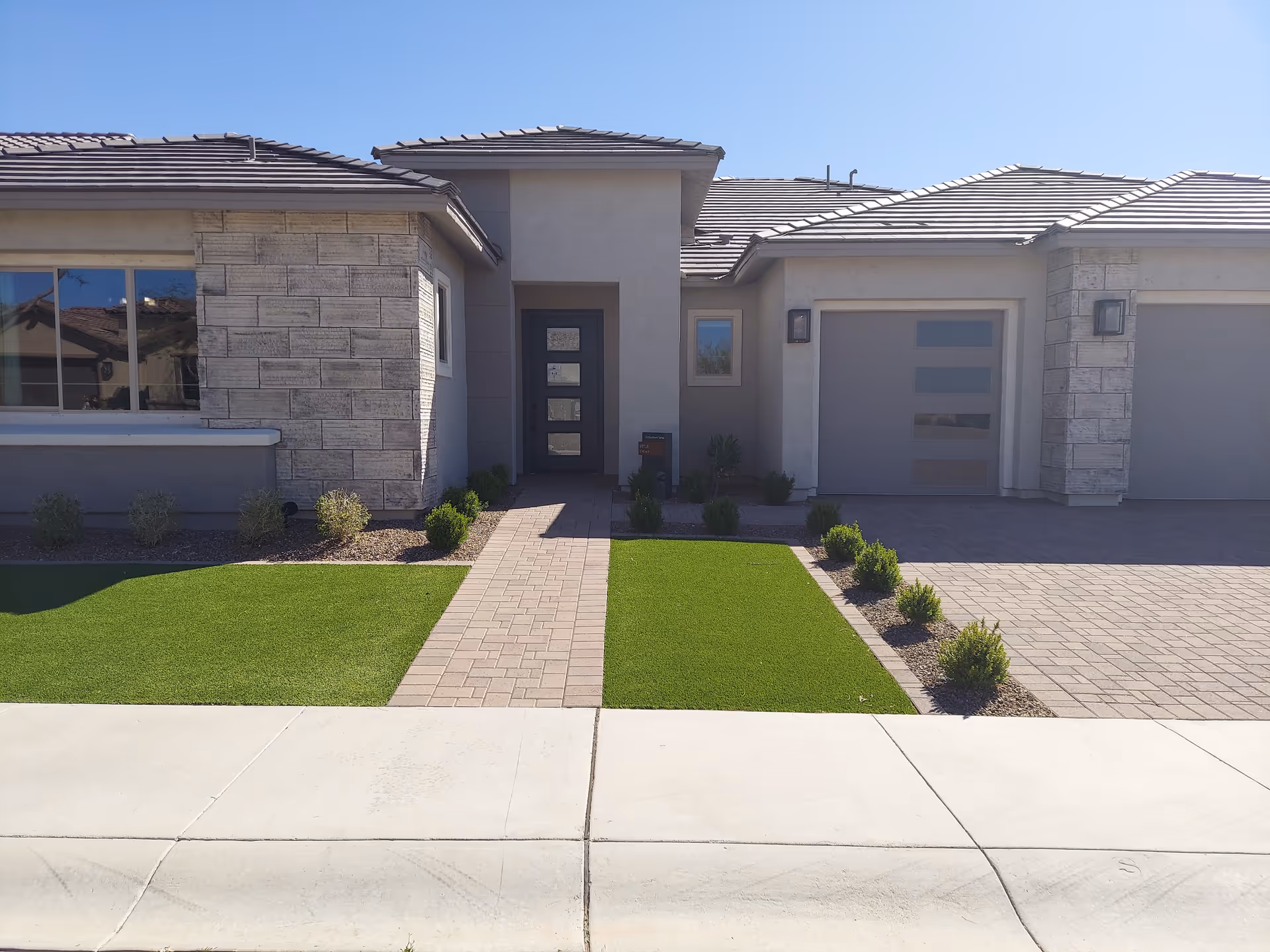 Sun City Festival facility exterior featuring stone accents, front entrance, two garage doors, and landscaped lawn.