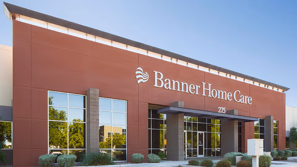 Modern senior care facility exterior with red facade and large glass entrance doors.
