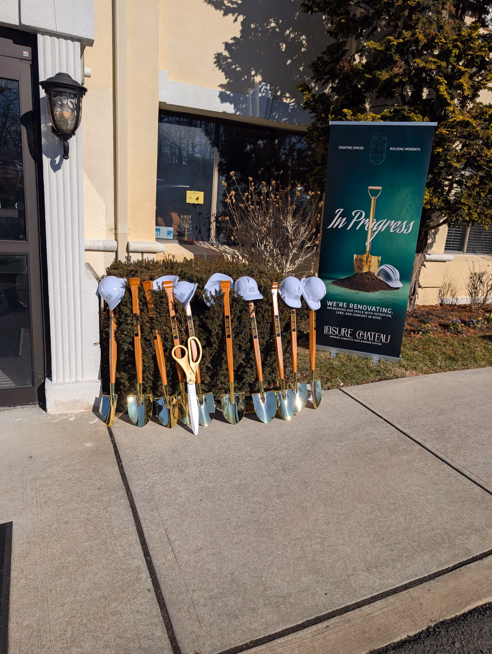 Shovels and white hard hats lined up outside a facility entrance with an In Progress banner