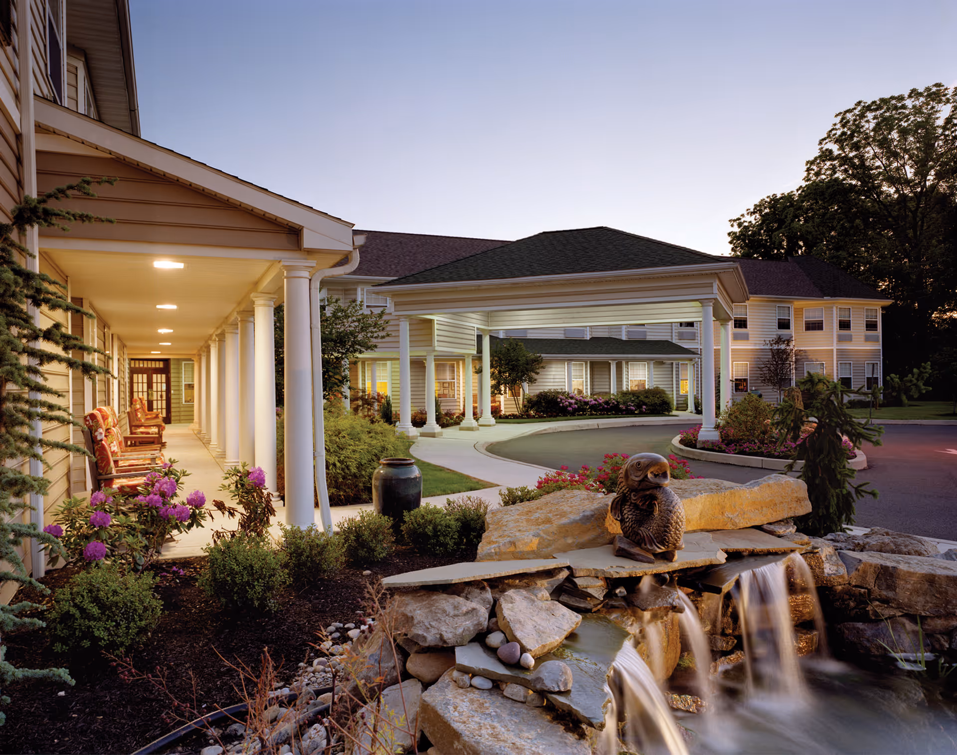 Exterior view of Dresher Estates by Priority Life Care showing veranda, fountain, and landscaped entrance.
