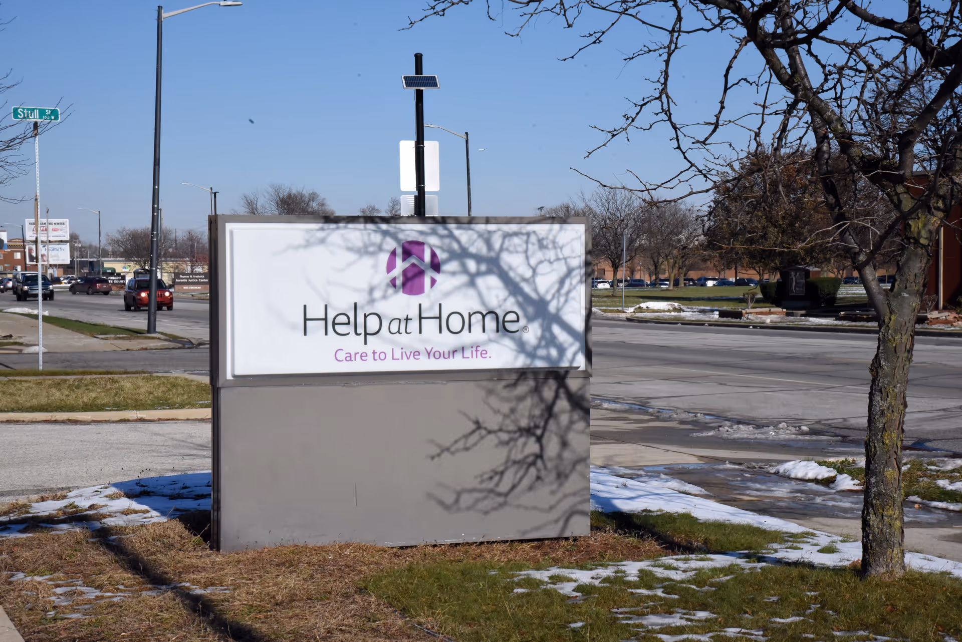 Outdoor signage for Help at Home on the building front by the street.