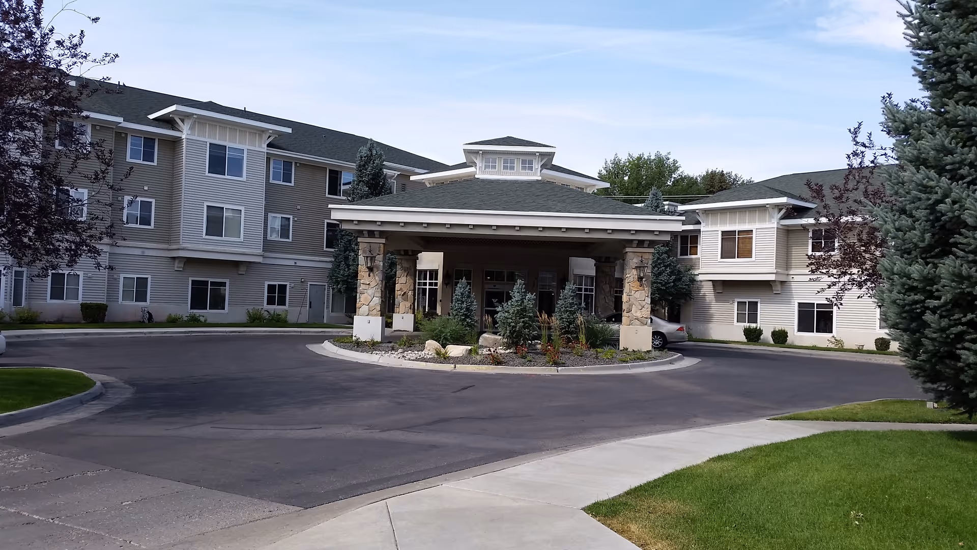 Exterior view of a senior living facility with a circular driveway and entrance.
