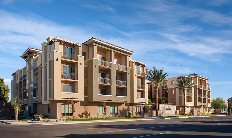 Exterior view of a modern beige senior living building with balconies.