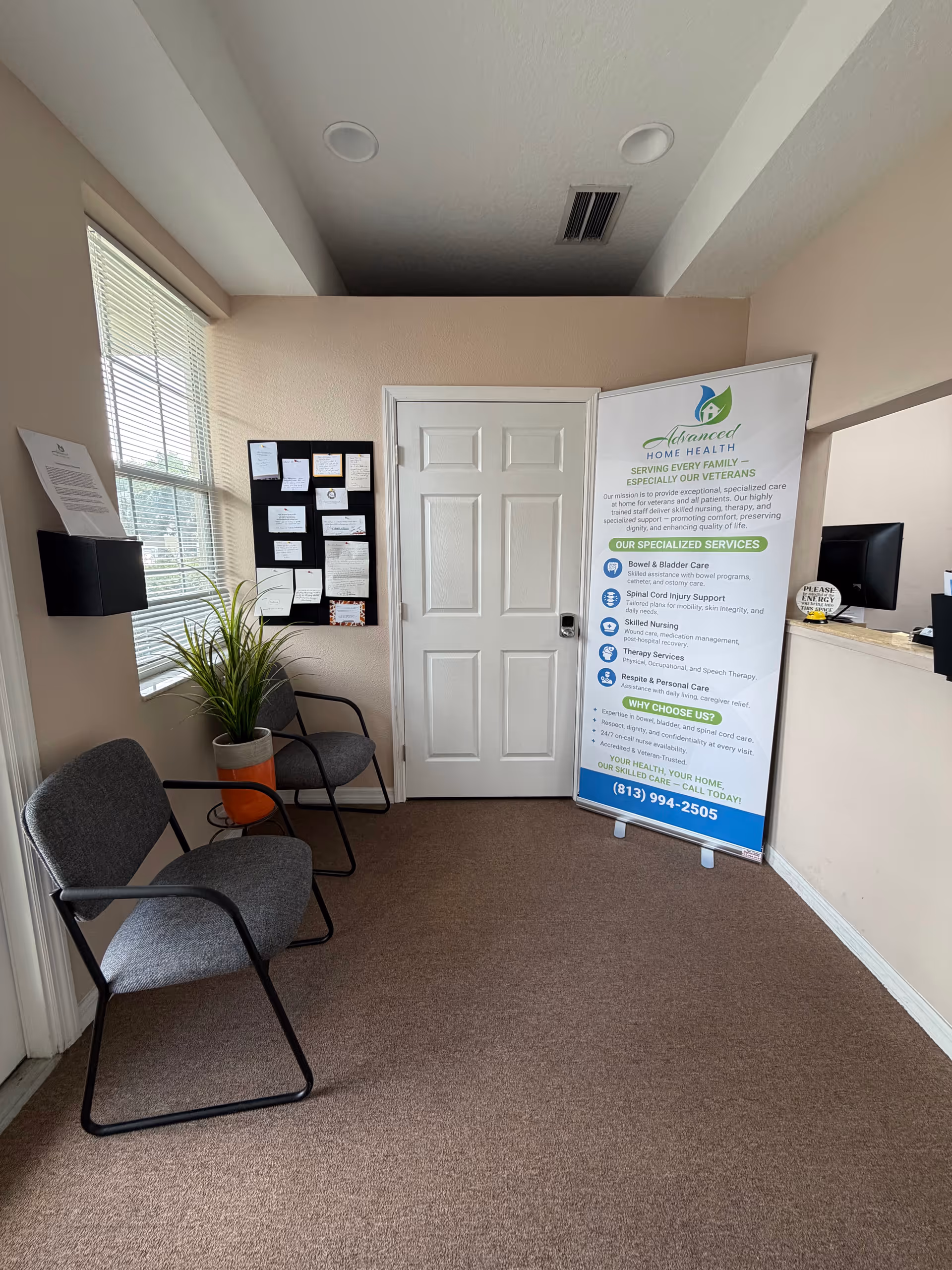 Interior waiting area at Advanced Home Health with chairs, banner, plant, and bulletin board.