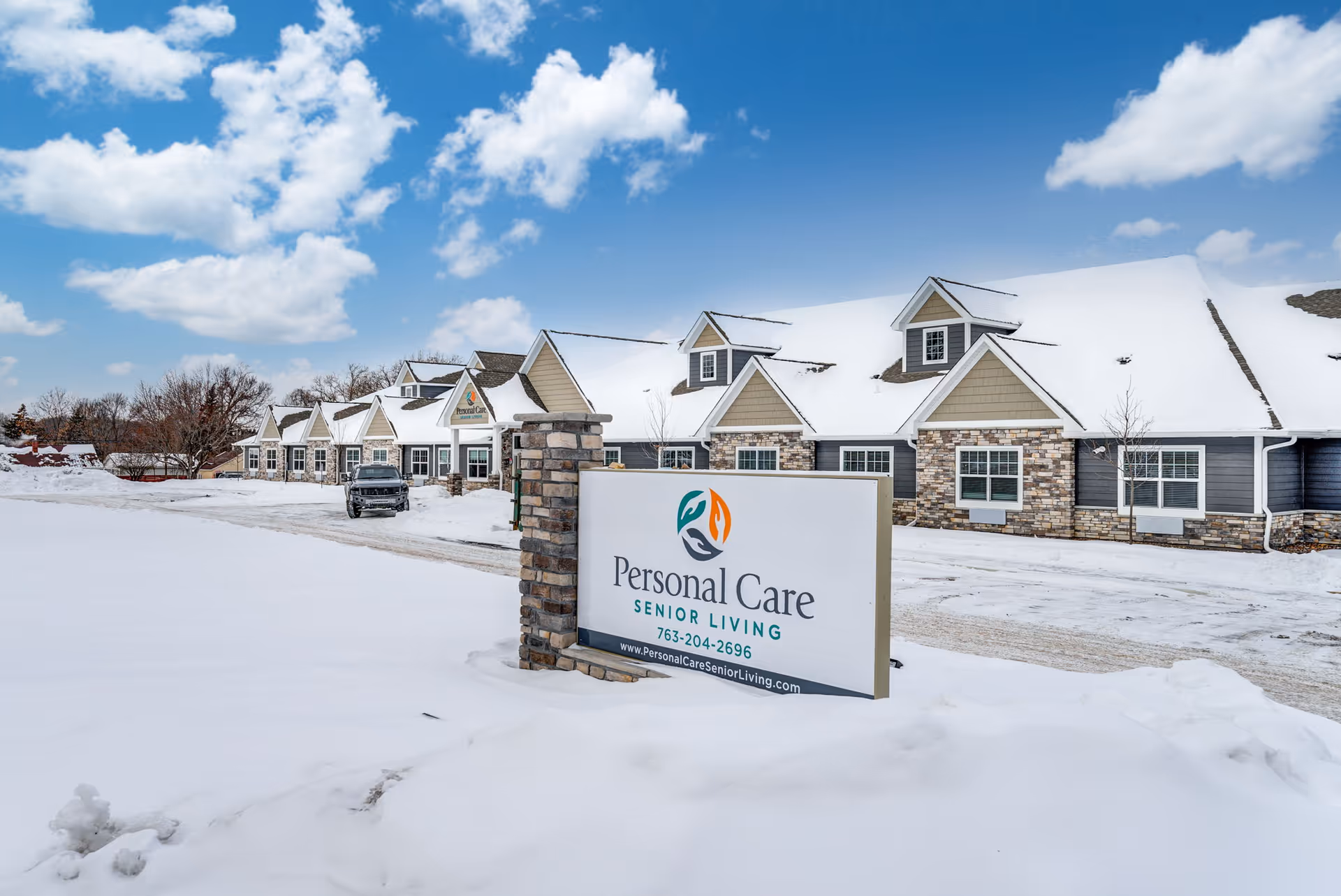 Front exterior of the Personal Care Senior Living facility with a prominent sign and snow-covered grounds.