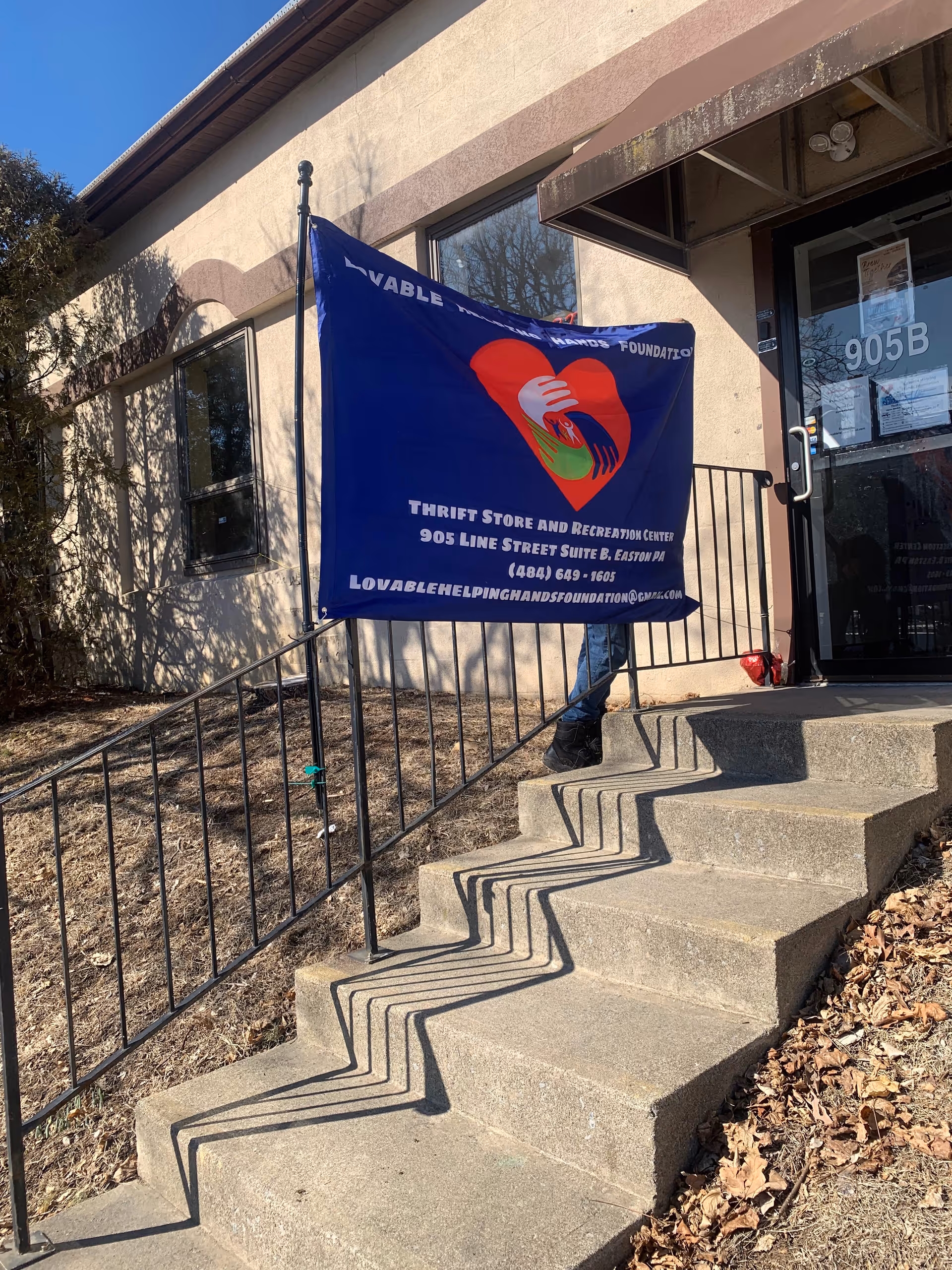Exterior storefront shows a blue banner on a railing near a building entrance.