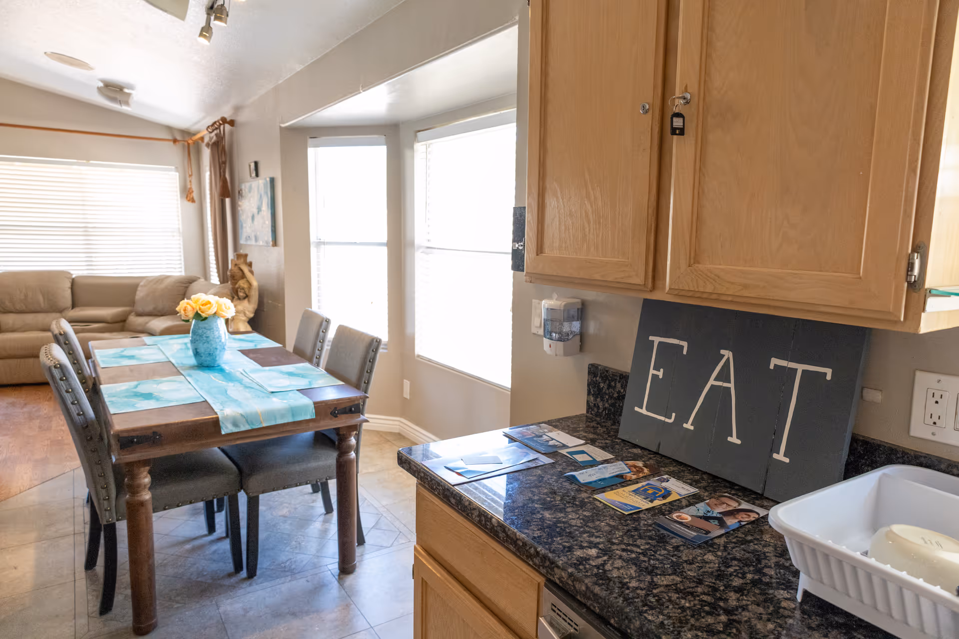 Open dining area with a table, chairs, and kitchen counter in a senior living home.
