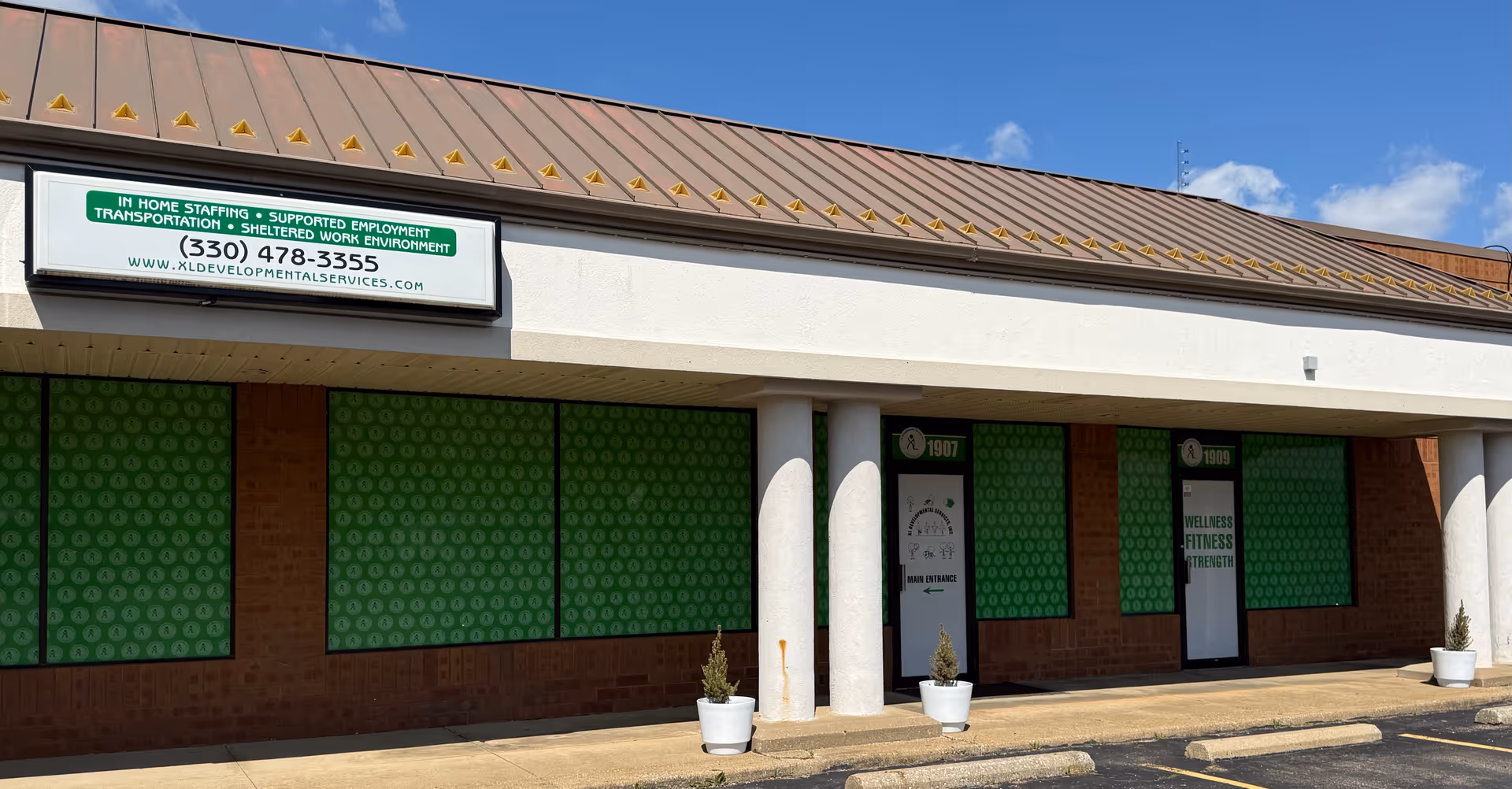 Front view of a single-story building with green storefront windows and XL Developmental Services sign.