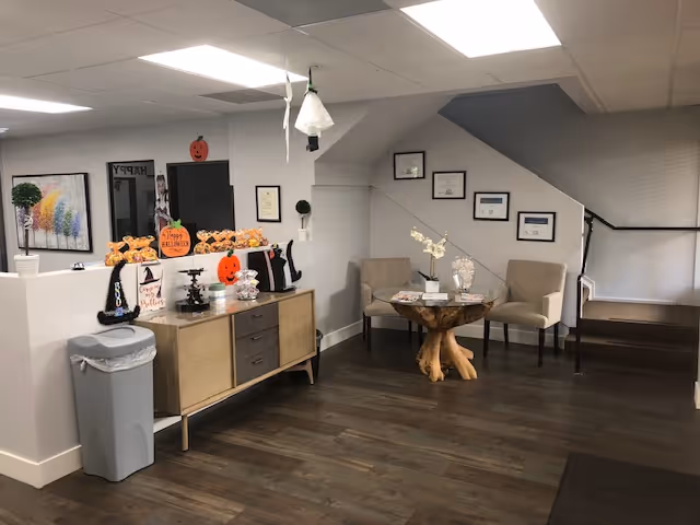 ApexCare lobby with Halloween decor, a wooden console, and seating near the staircase.