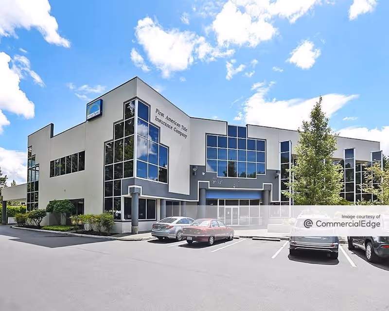 Modern two-story commercial building with large glass windows and a front parking lot.