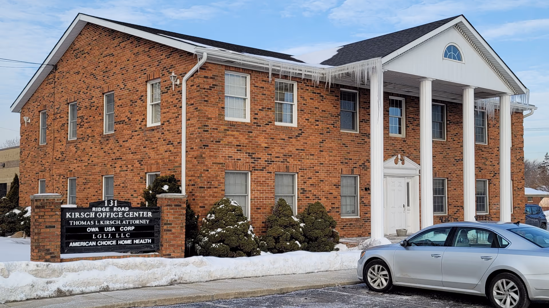 Exterior view of a brick building with white columns and a snow-covered landscape.