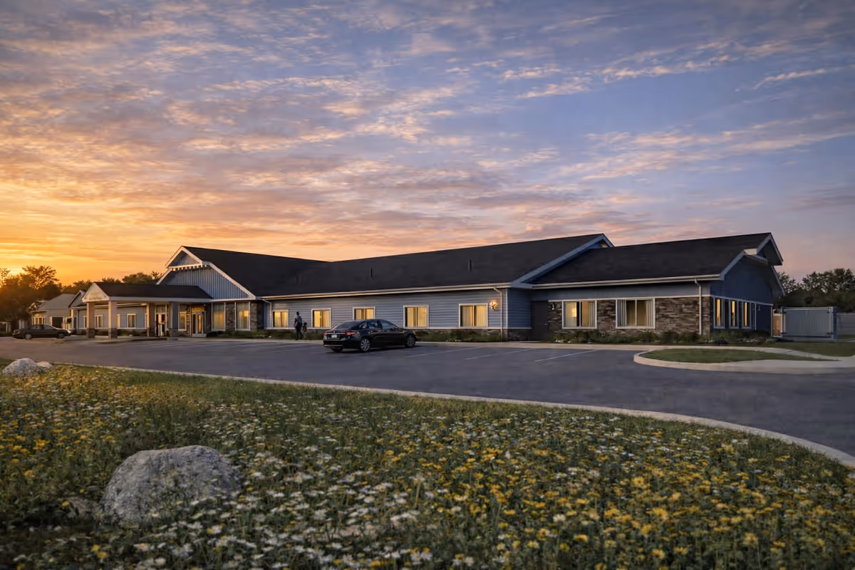 Exterior view of Maplewood Meadow Assisted Living at sunset with parked cars.
