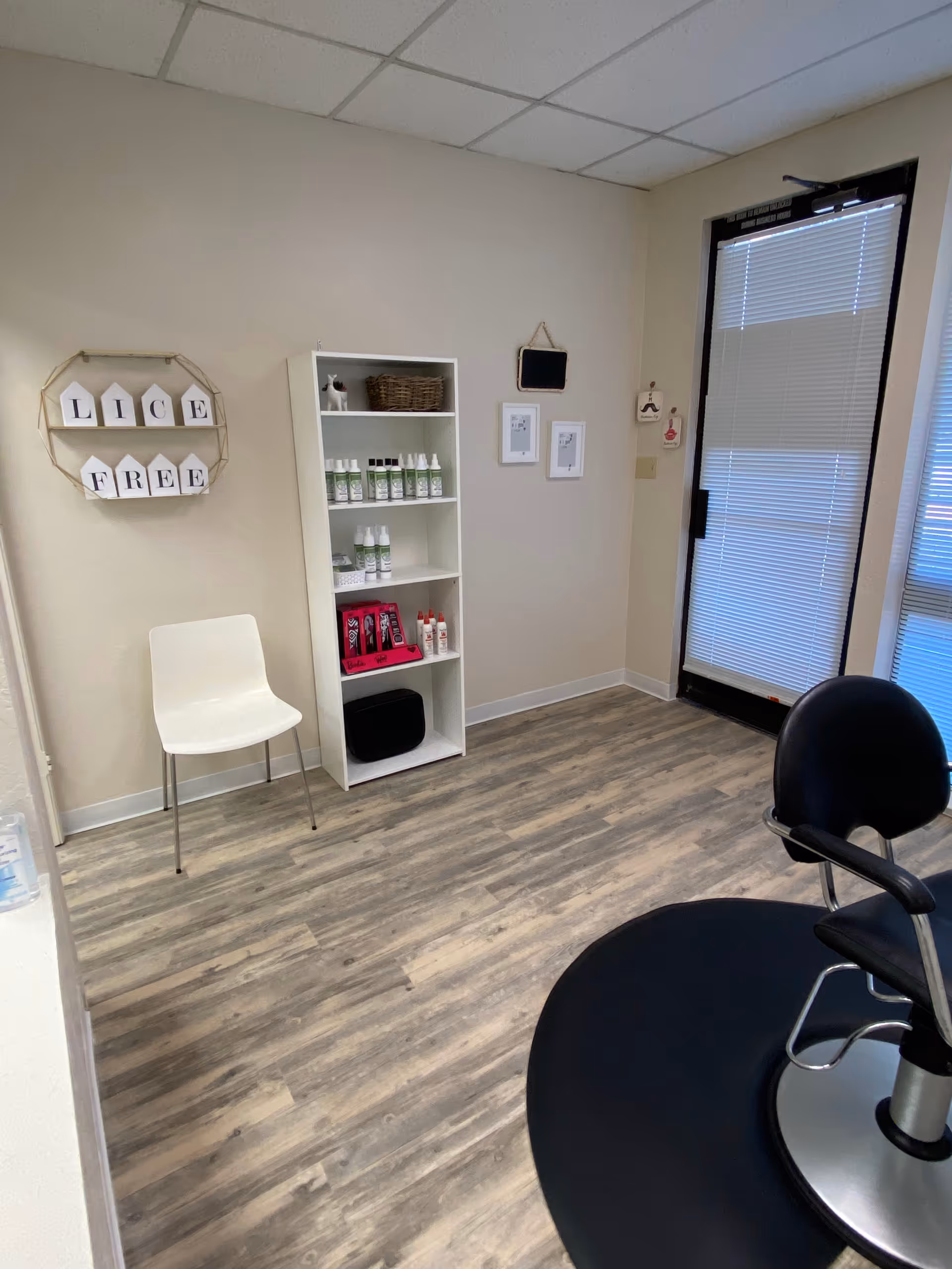 Treatment room with a white chair, shelf of lice products, and a Lice Free sign.