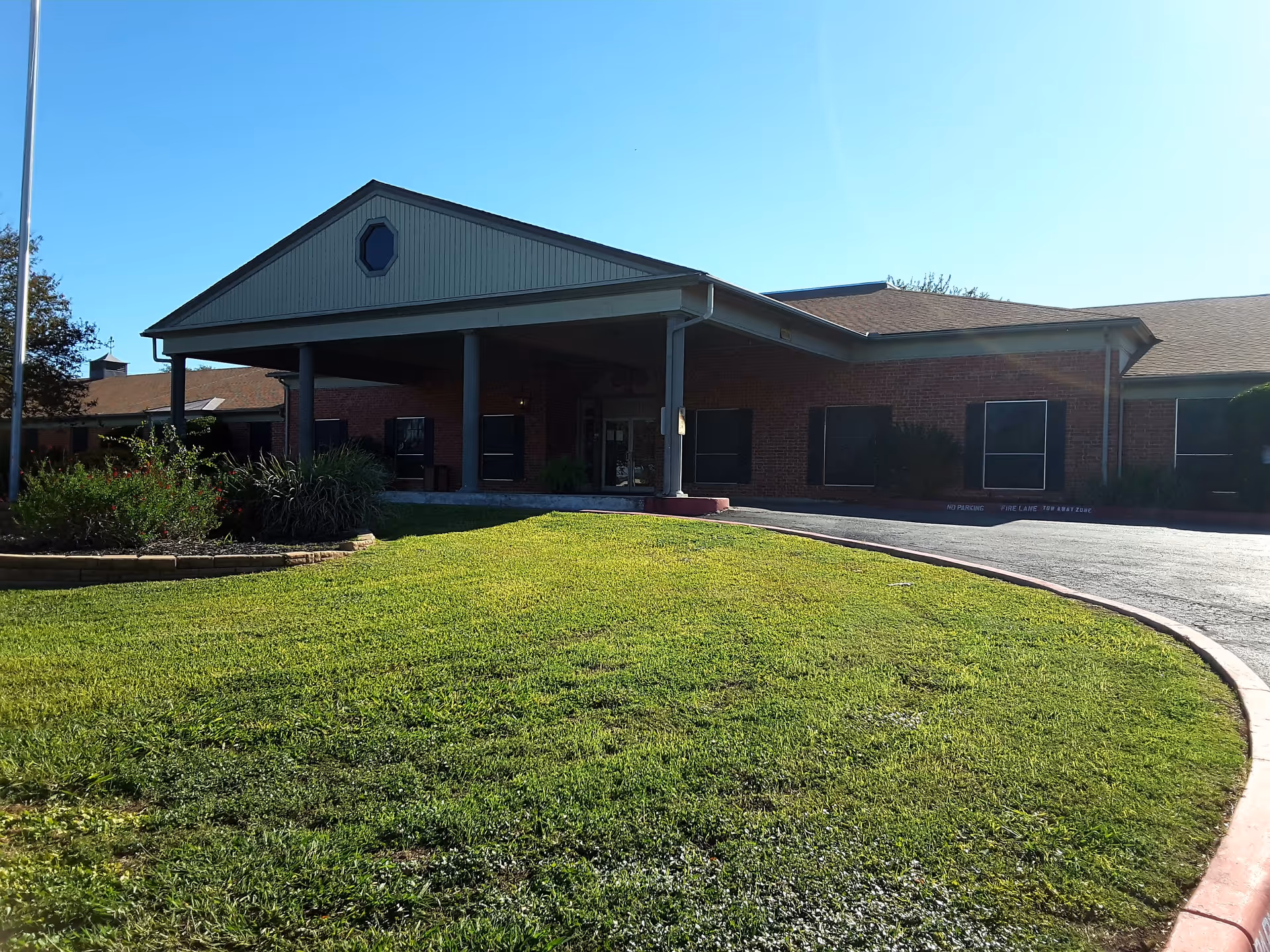 Brick nursing facility with a covered entrance and manicured lawn at the front
