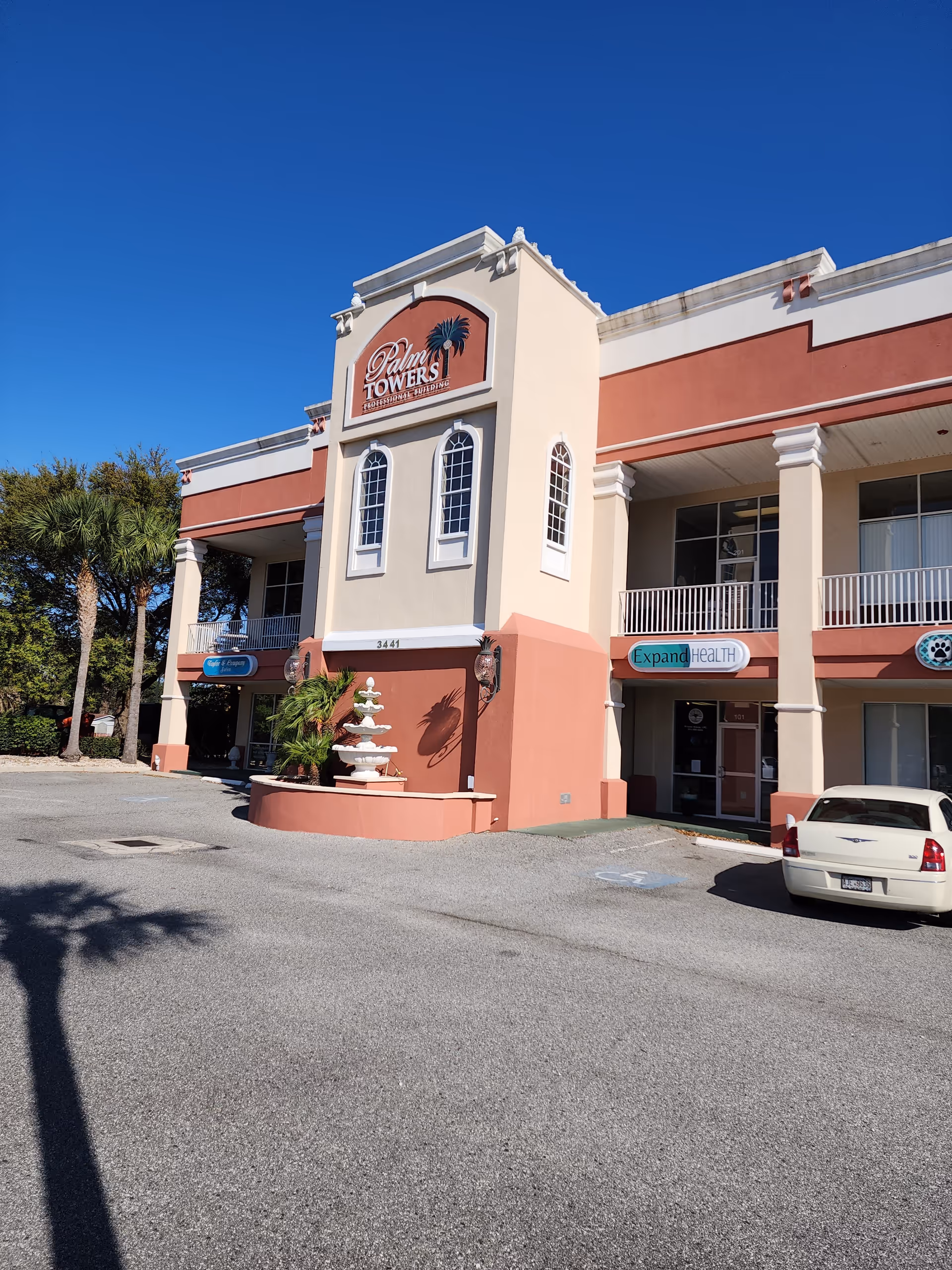 Exterior view of a senior living center with Palm Towers sign and fountain.