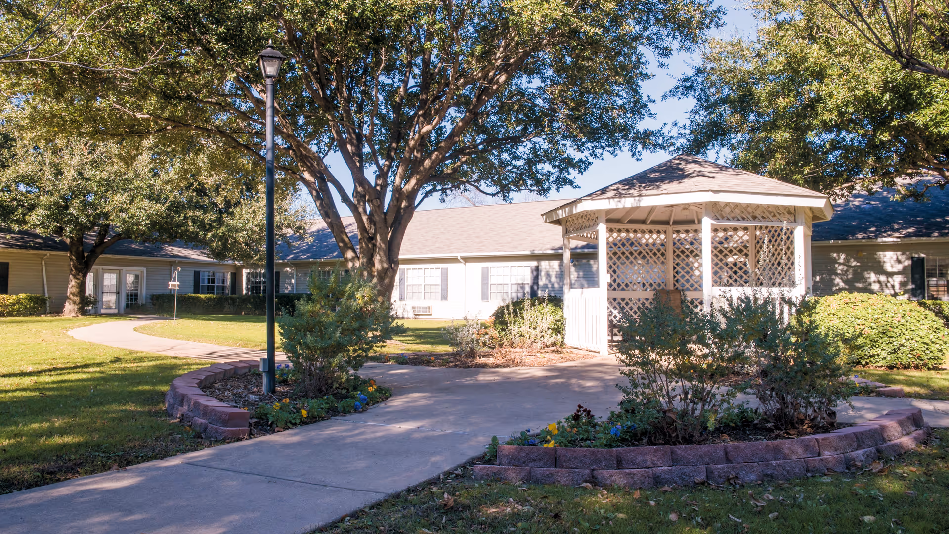 Exterior view of Brookdale Tanglewood Oaks with gazebo, walkway, and landscaped grounds.