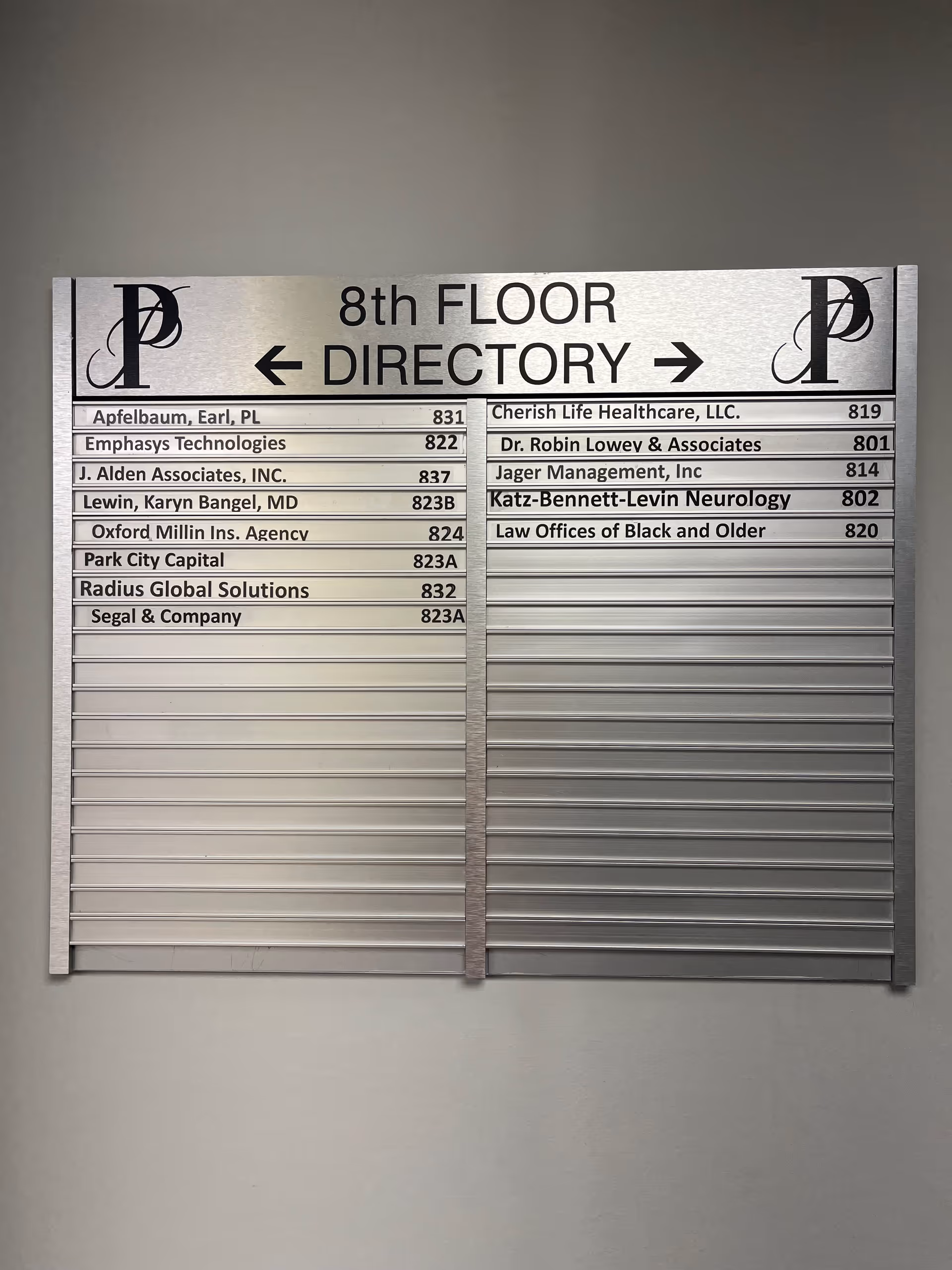 Metal directory sign on an interior wall listing 8th floor tenants.