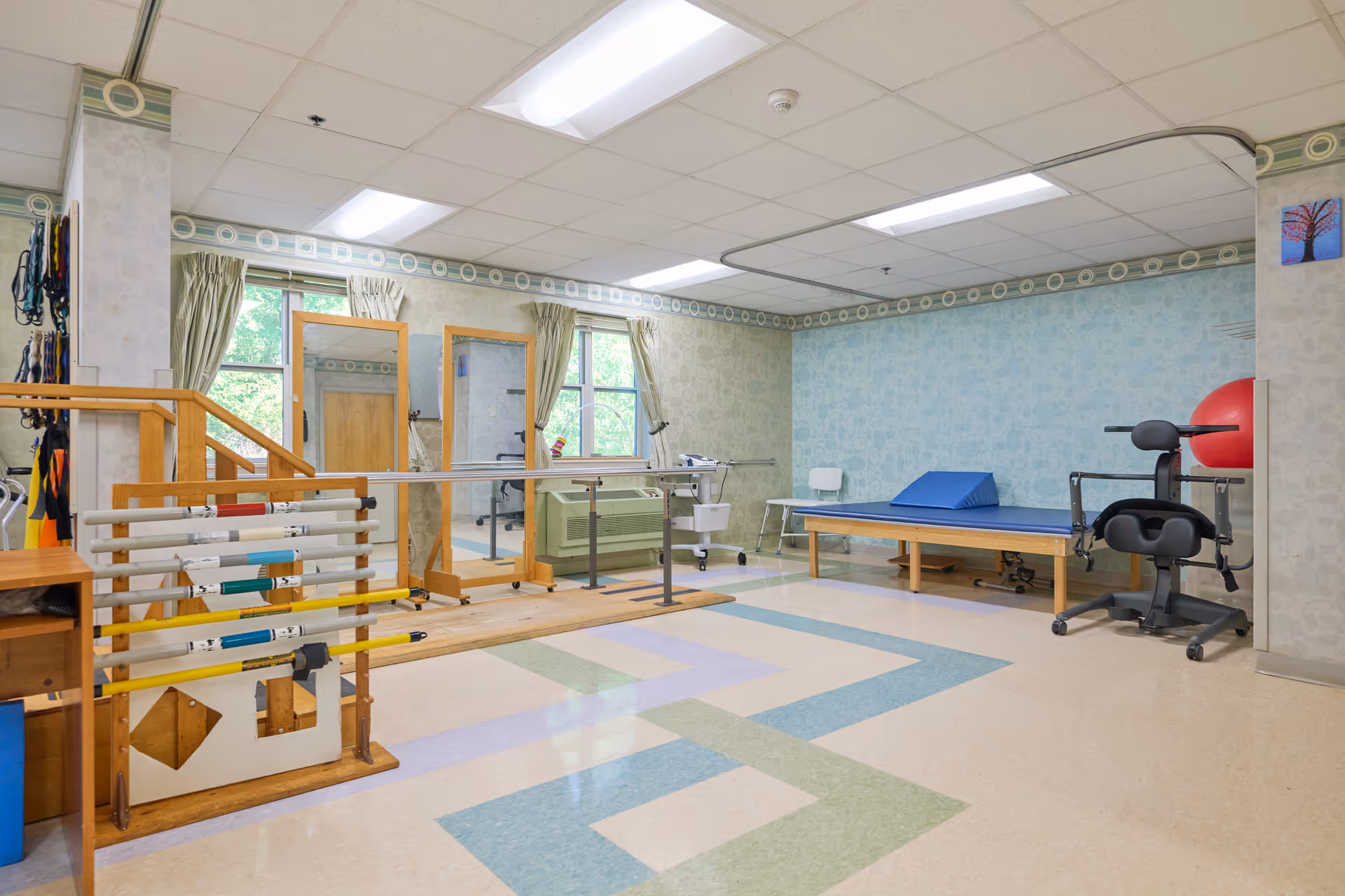 Rehab exercise room with parallel bars, mats, and gym equipment in a senior facility.