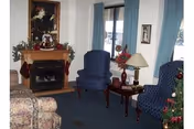 Cozy living room with blue patterned chairs, a fireplace, and a Christmas tree.
