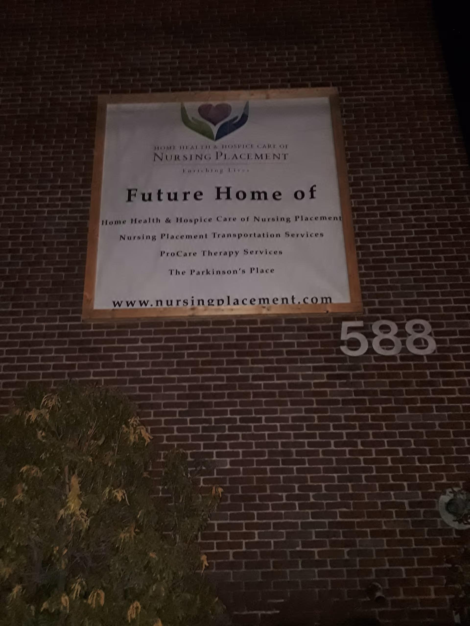 Nighttime exterior view of a brick building with a large banner sign.