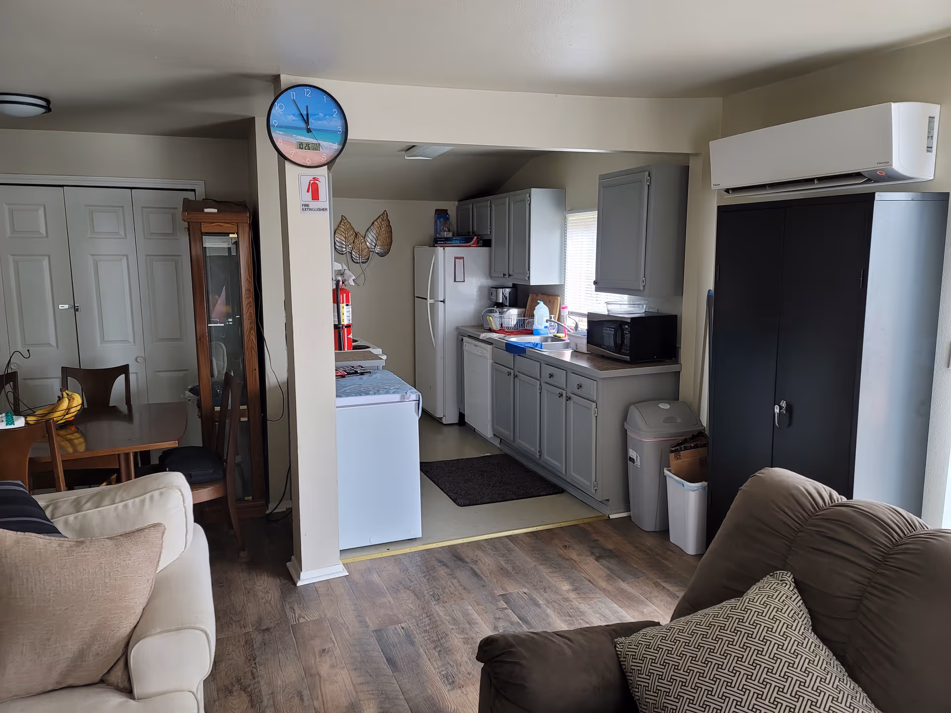 Open living area with couch in foreground and compact kitchen along back wall.
