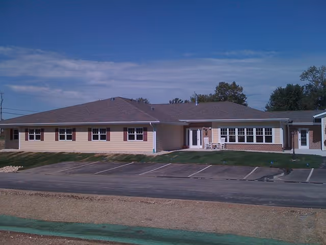 Single-story beige senior living facility with a brown roof and a parking lot.