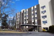 Front exterior of a multi-story nursing facility with a covered entrance and blue sky.