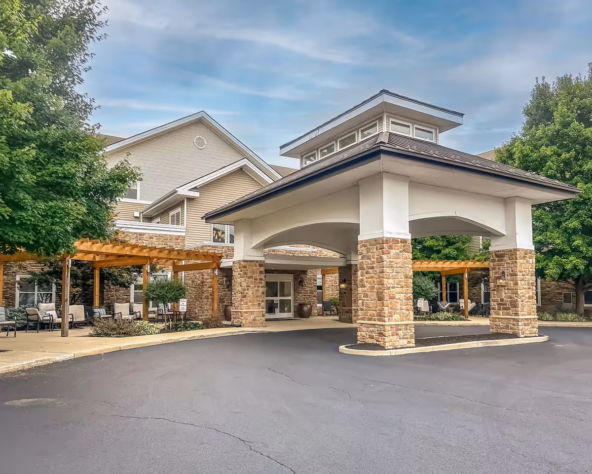 Entrance to Pinebrook of Milford, a senior living facility, with a porte-cochere and outdoor seating.