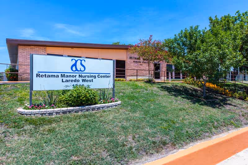 Exterior view of Retama Manor Nursing Center Laredo West with landscaping and a sign.