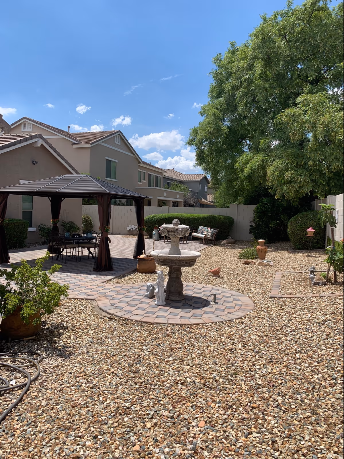 Outdoor courtyard with gazebo, fountain, brick patio, and decorative gravel.