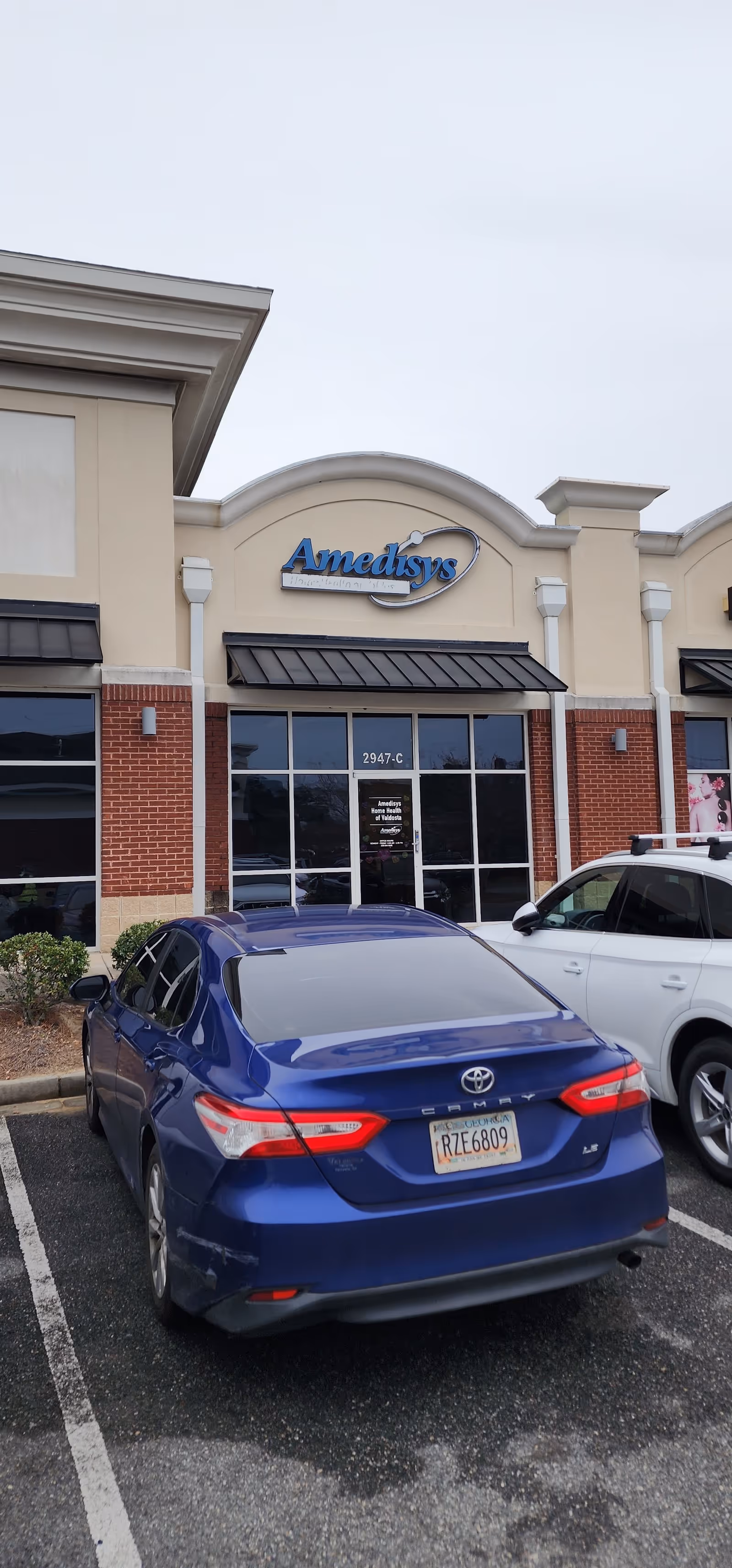 Exterior view of Amedisys Home Health Care building with blue and white cars.