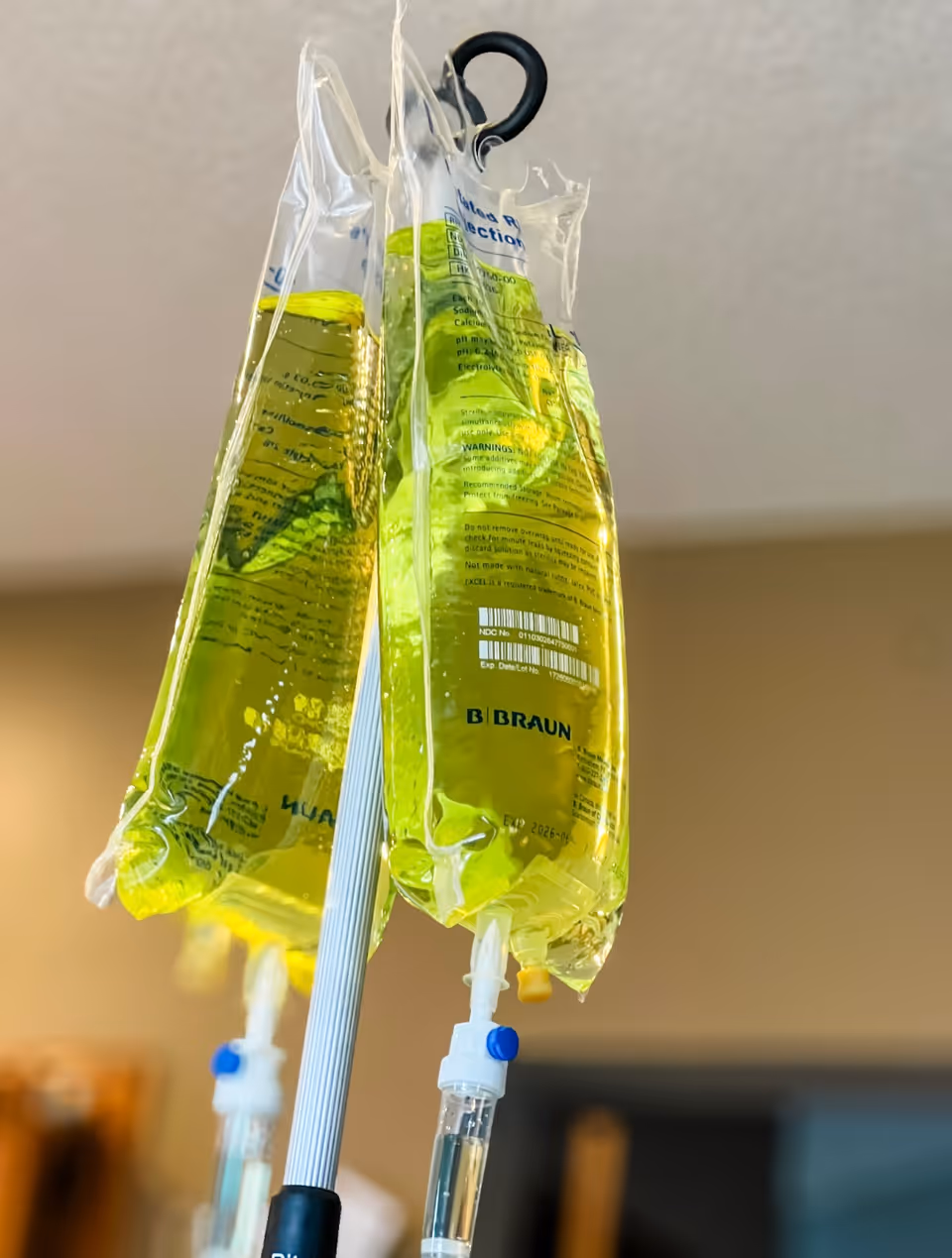 Close-up of IV bags hanging from an infusion pole in a clinical room.
