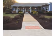 Front view of The Woodlands Health And Rehab Center with a walkway and landscaped front yard.
